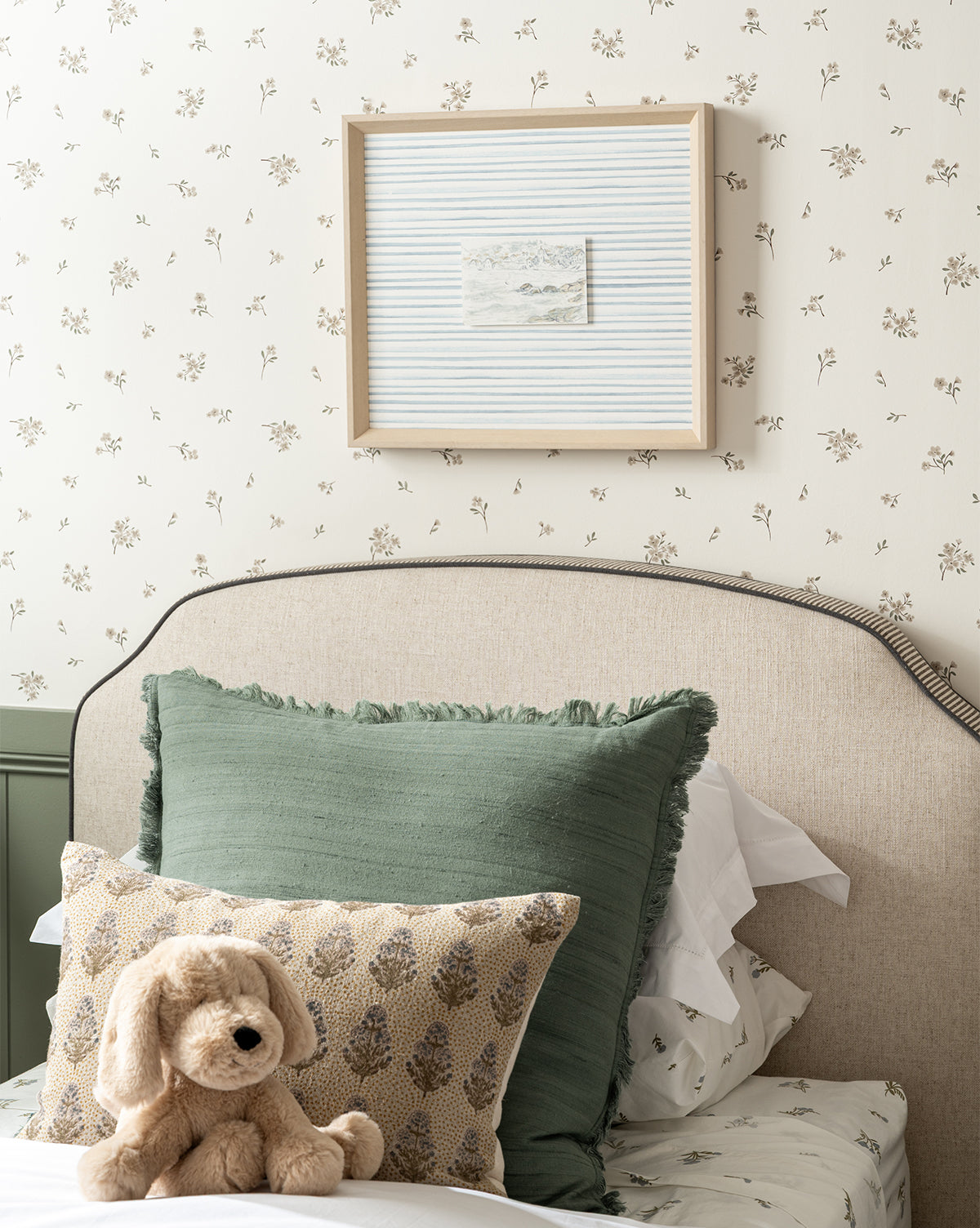 Bedroom with floral wallpaper, green pillow, patterned pillow, and teddy bear.