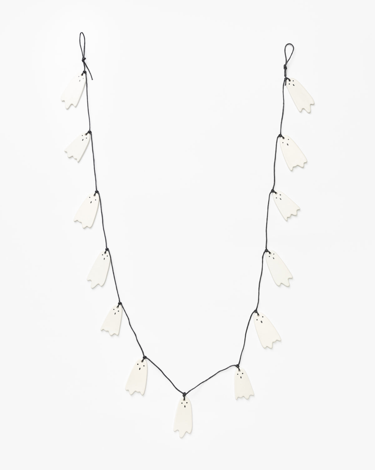 The 3 Ceramic Ghost Garland features small black-eyed ceramic ghosts evenly spaced on a black string, perfect for Halloween decor, by McGee & Co.