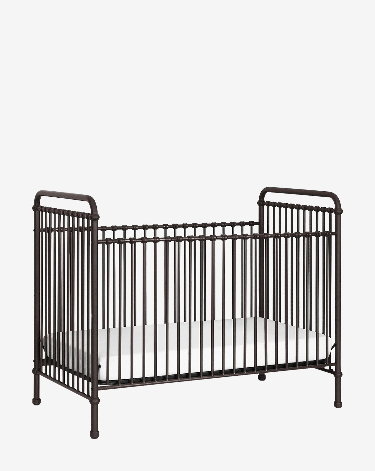 The Abigail 3-in-1 Convertible Crib by Million Dollar Baby features dark metal, vintage-style vertical bars and a white mattress, creating a timeless nursery look that stands out against a plain white background. McGee & Co.