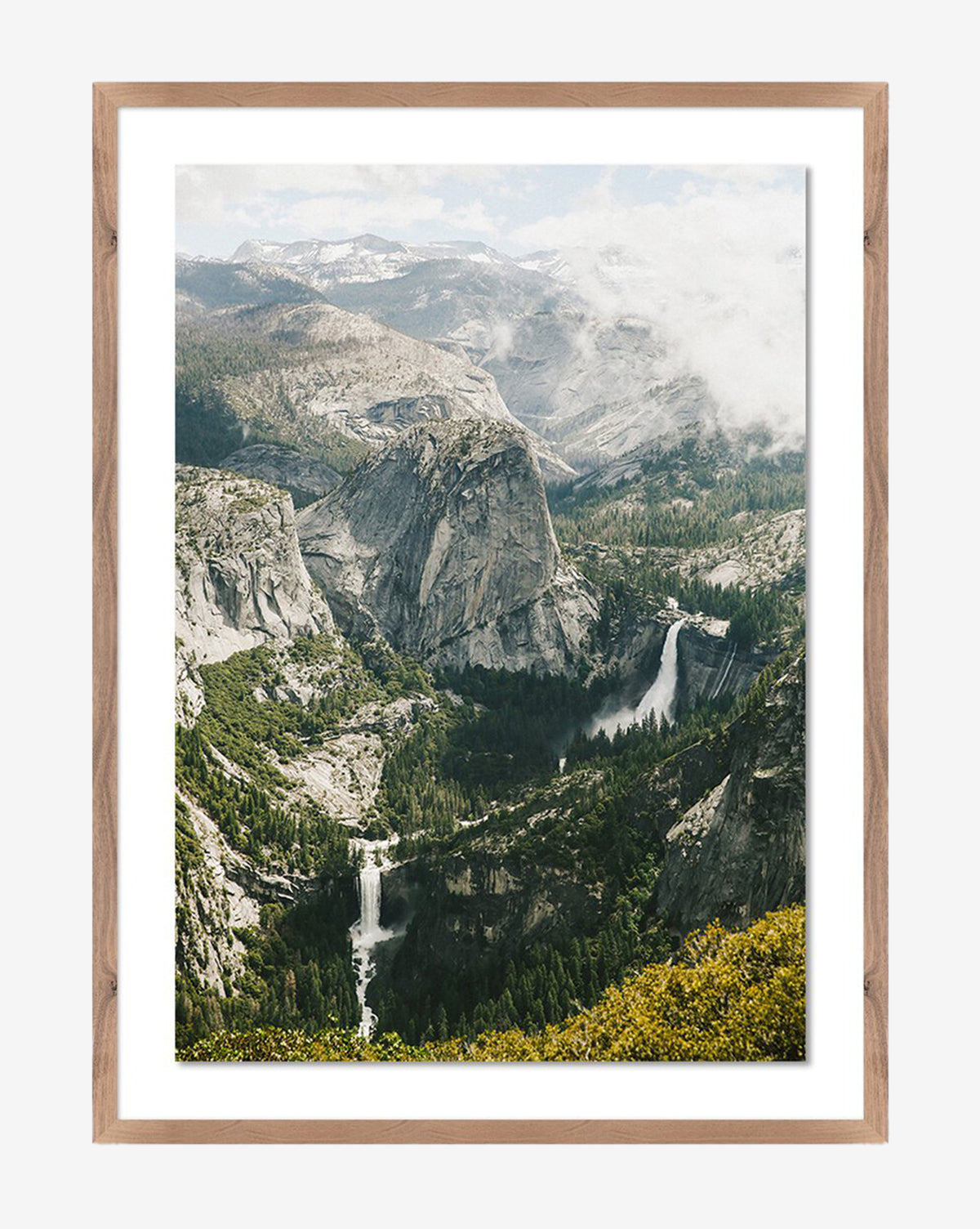 Above The Clouds by Wesley and Emma Teague is a framed photograph featuring a granite peak, lush forests, two waterfalls, and misty clouds in a walnut-finished wood frame for elegant, gallery-quality appeal by McGee & Co.
