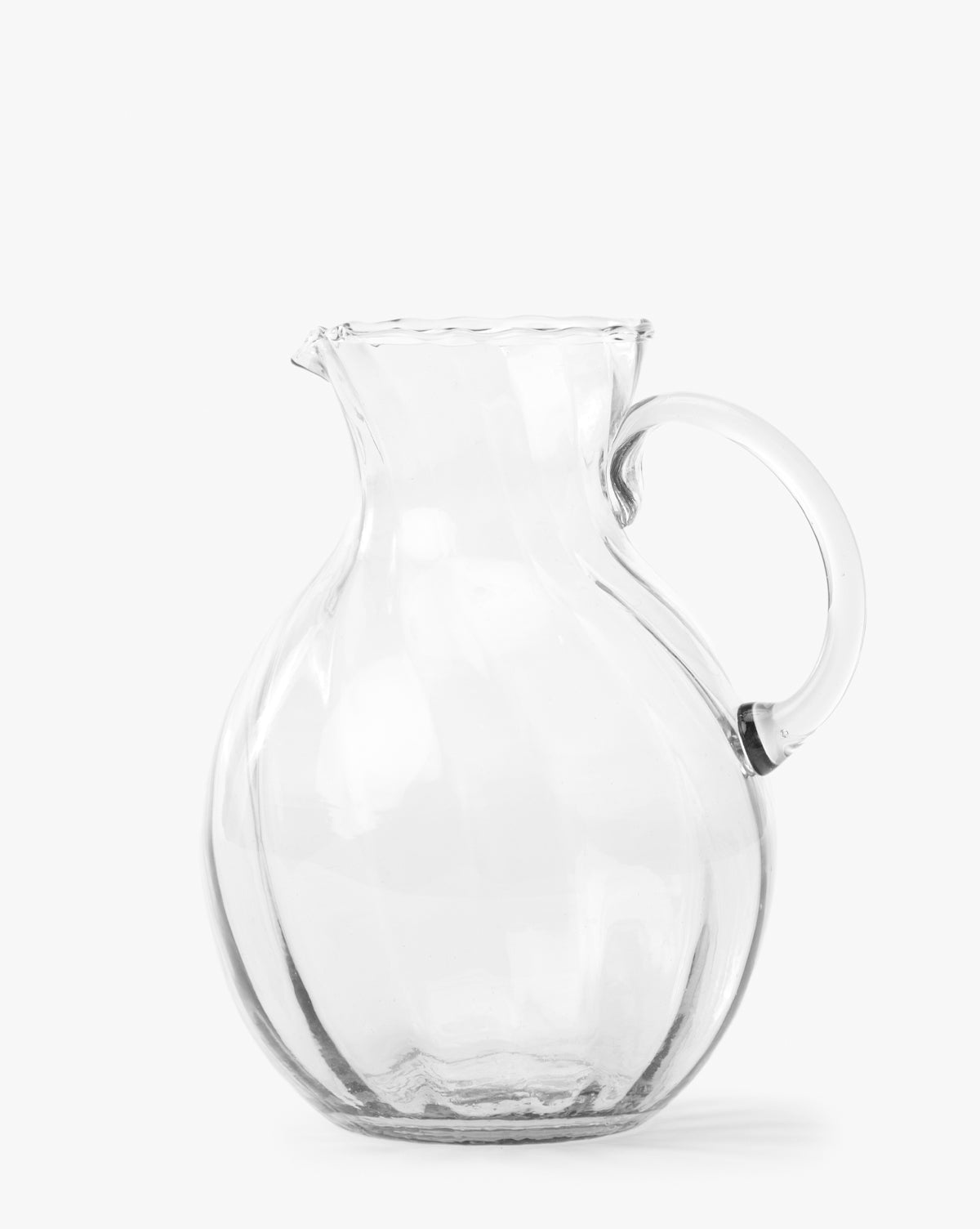 The Adderley Pitcher, made of clear mouth-blown glass with a rounded body, small spout, and curved handle, is displayed against a plain white background by McGee & Co.