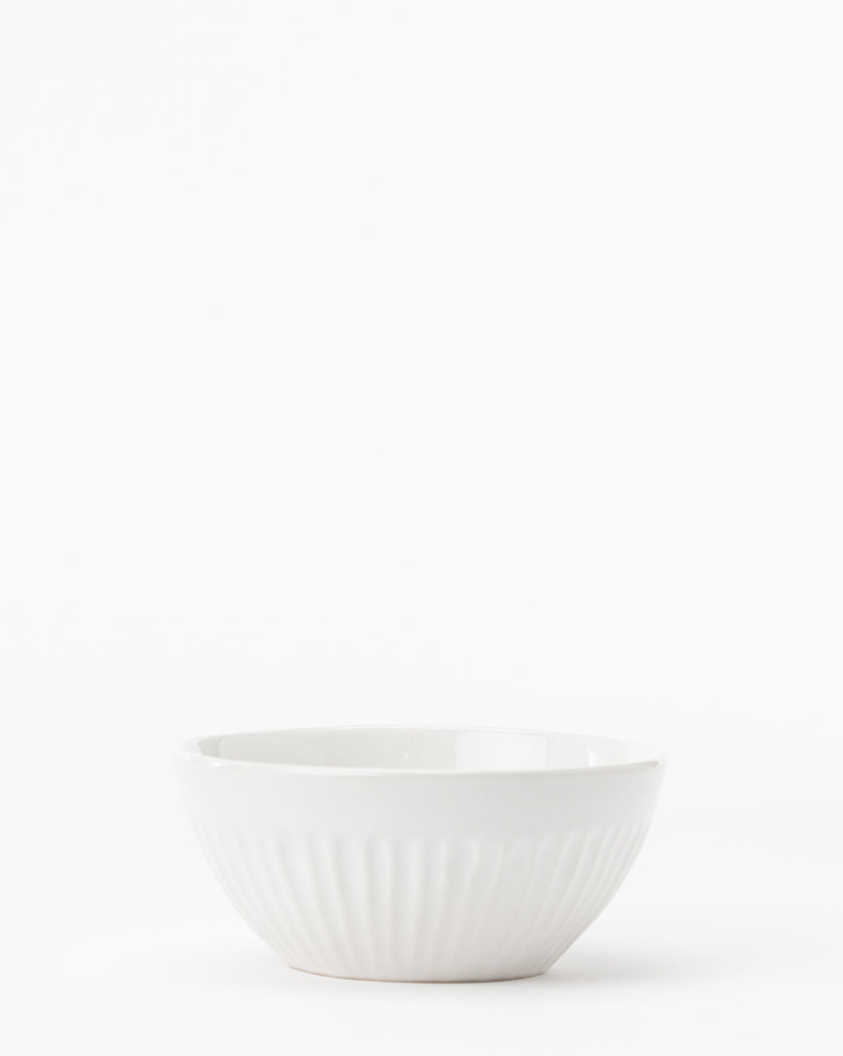 The Adele Bowl, a small white ceramic piece with a subtle ridged texture, sits on a plain white background, highlighting its timeless design, by McGee & Co.