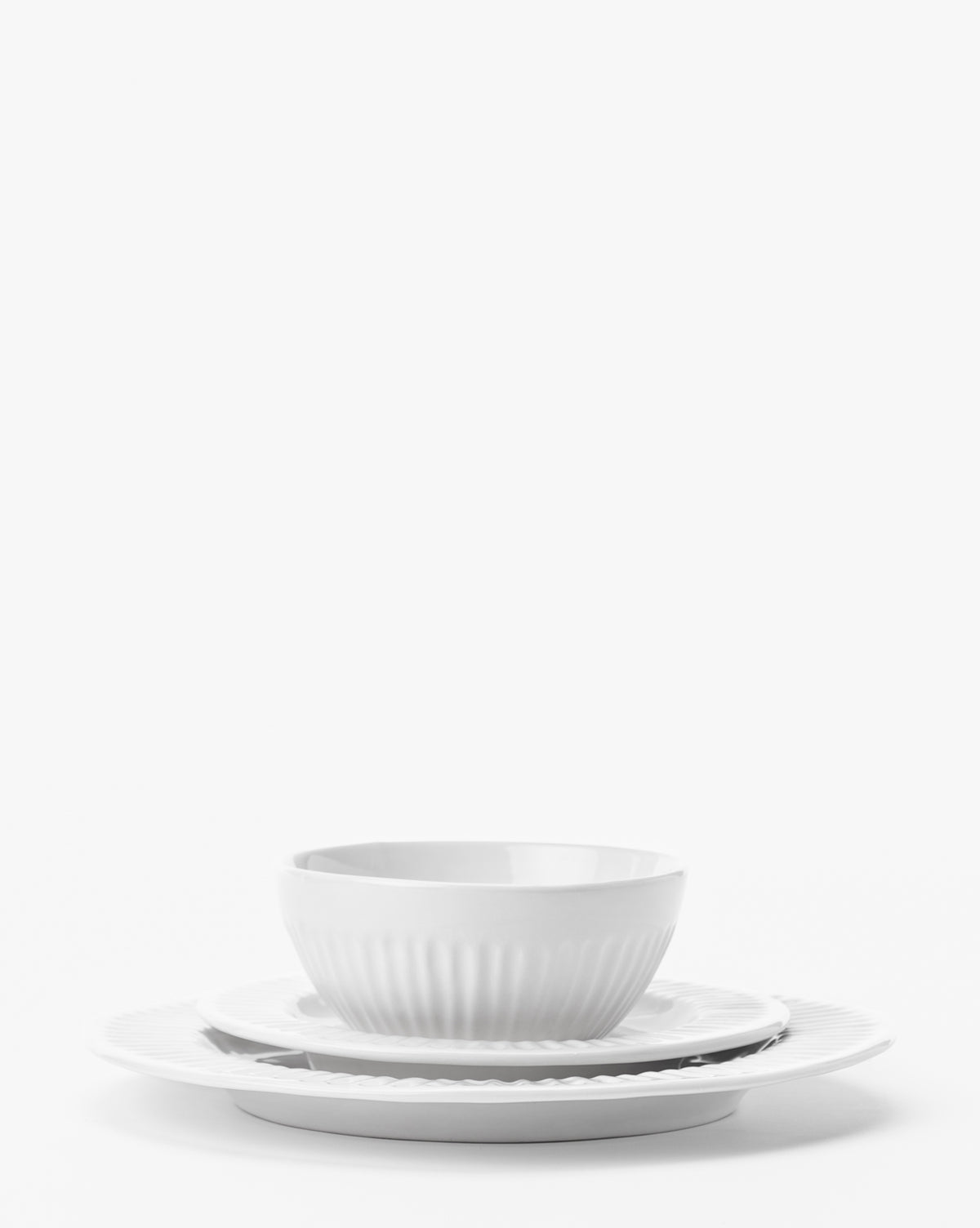 An Adele White Dinner Plate from a set of 4, featuring a subtle textured pattern and timeless design, is stacked with a ceramic bowl and larger plate against a plain white background, by McGee & Co.