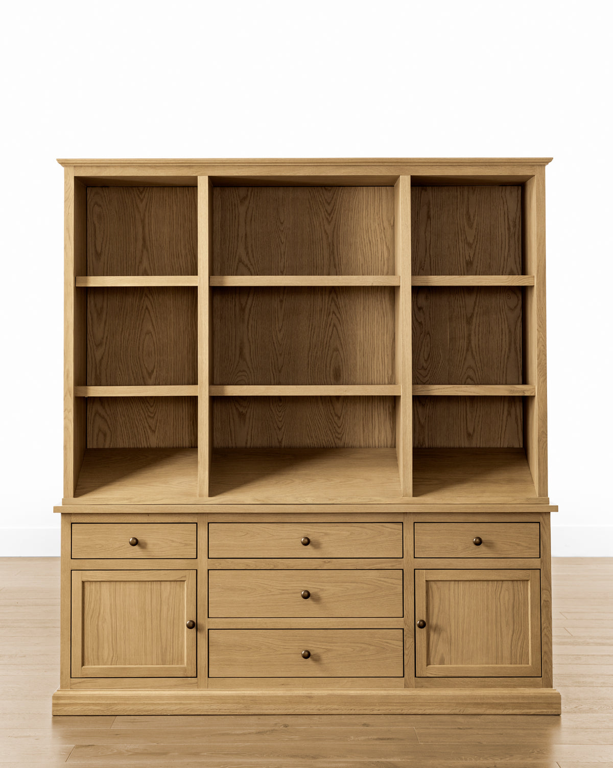 The Adler Oak Cabinet by BOUVRIE INTERNATIONAL VIET NAM CO., LTD. is a spacious wooden storage unit with three open shelves, six drawers, and two lower cabinets, shown on a light wood floor against a plain white background. McGee & Co.