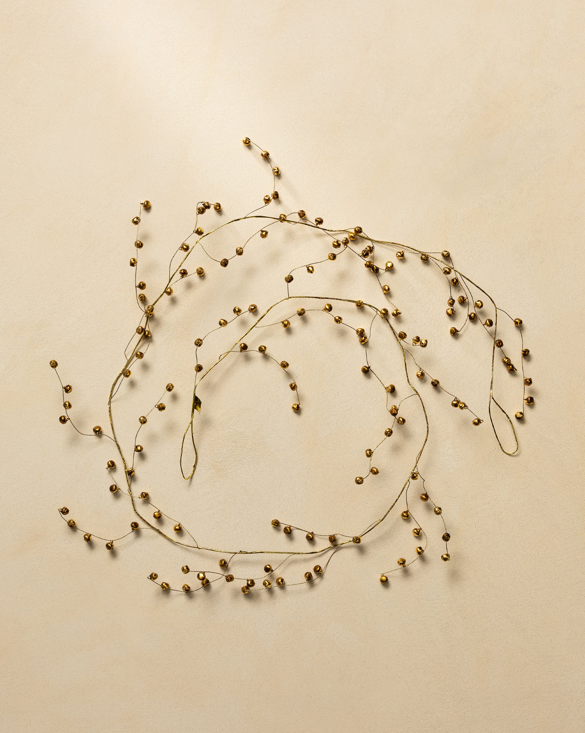 The 6' Angelica Gold Garland features delicate gold beads on thin wire, arranged in loose circles on a light beige background to add an elegant touch to your holiday decor, by McGee & Co.