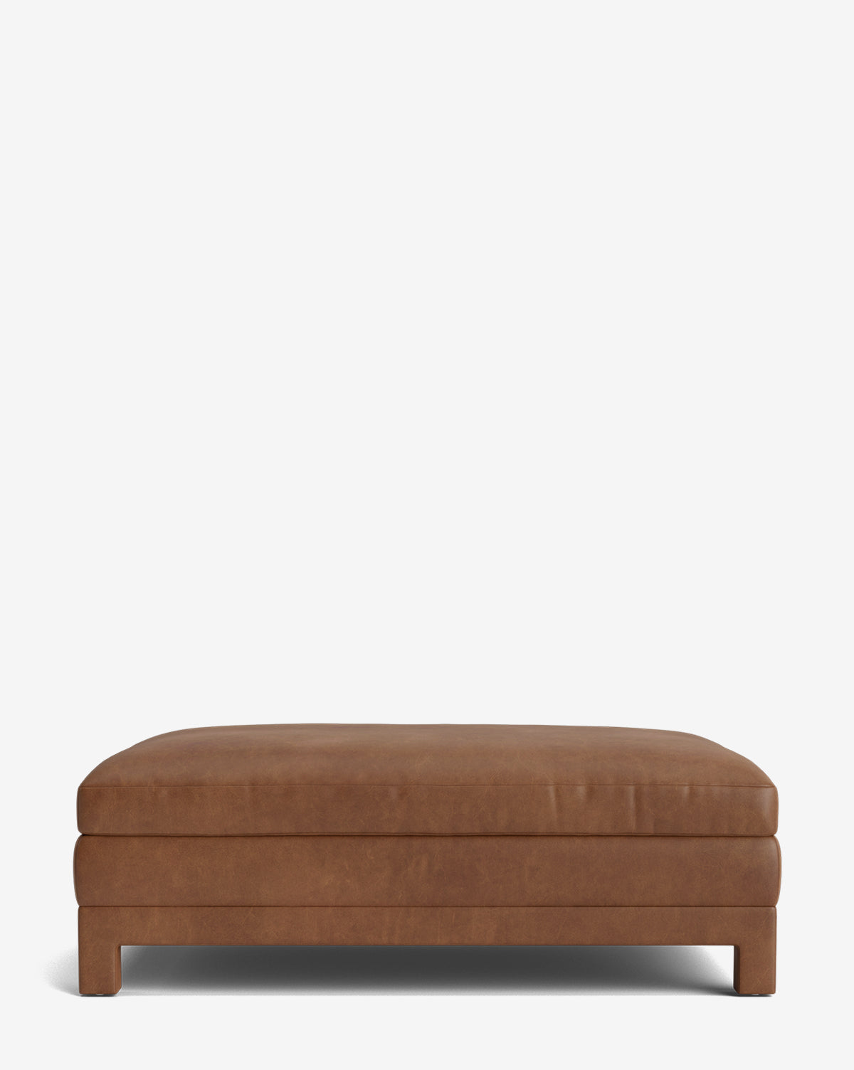 The Appoline Ottoman is a rectangular, low-profile modern piece in brown leather, featuring a minimalist design, flat top, and four short legs, displayed against a plain white background by McGee & Co.