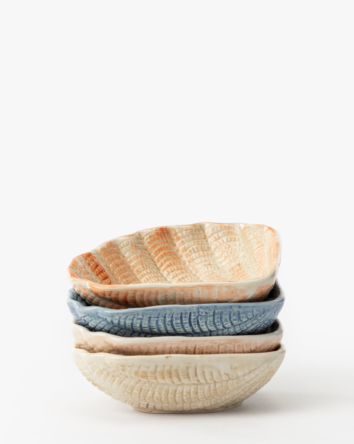 The Aurelie Shell Shaped Bowls (Set of 4) feature coastal-inspired, textured stoneware in cream, blue, and light orange tones. Each bowl has wavy edges and a shell shape, all set against a plain white background by McGee & Co.