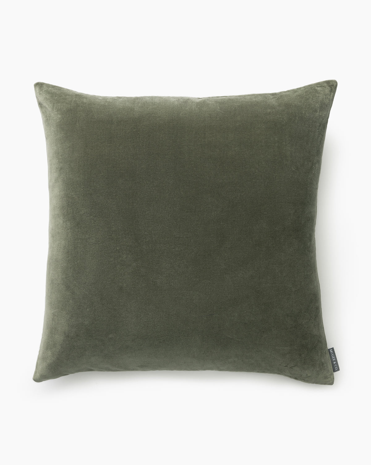 The Bellevue Velvet Pillow Cover is a square, olive green, stone-washed velvet cover with a soft texture. Displayed against a white background, it features a small fabric tag on one side, by McGee & Co.