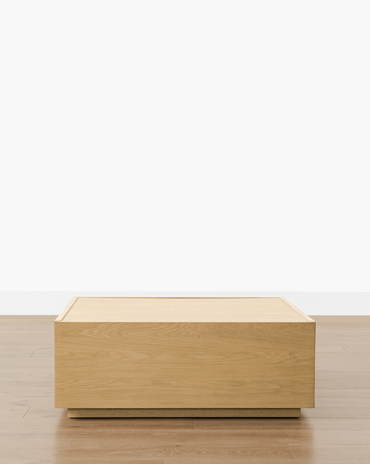 The Bentley Coffee Table stands on a light brown wood floor against a plain white wall, offering a clean, minimalist look, by McGee & Co.