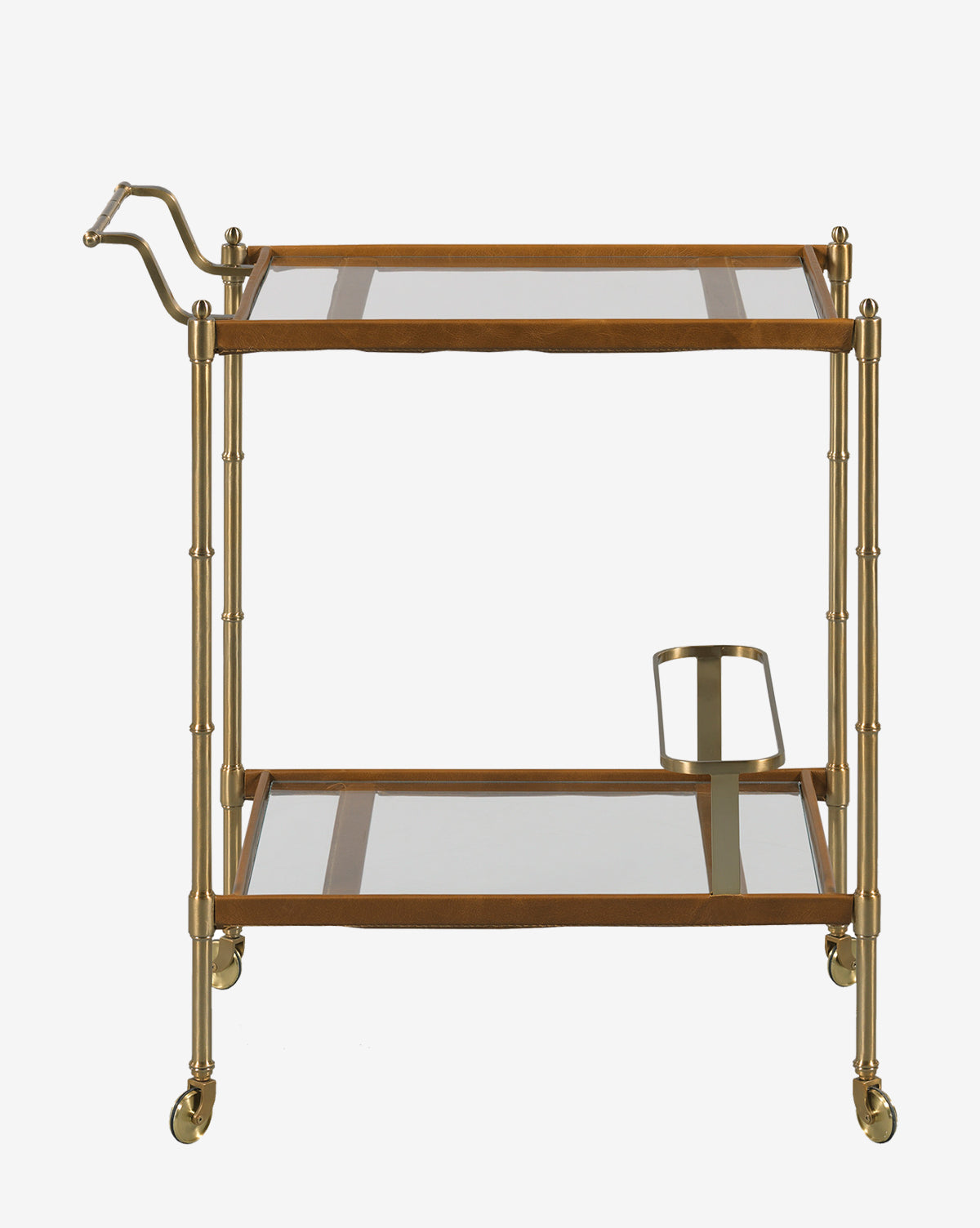 The Bexley Bar Cart showcases a brass bamboo-style frame, two glass shelves, a left-side handle, a metal bottle holder underneath, and four caster wheels for effortless movement, by McGee & Co.
