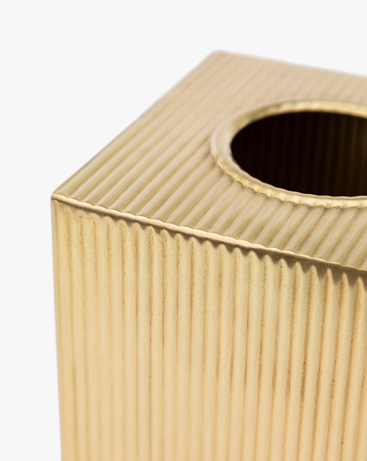 Close-up of the Calvert Brass Tissue Box Cover, an elegant gold-colored rectangular cover with fluted sides and a round top opening, displayed against a white background, by McGee & Co.