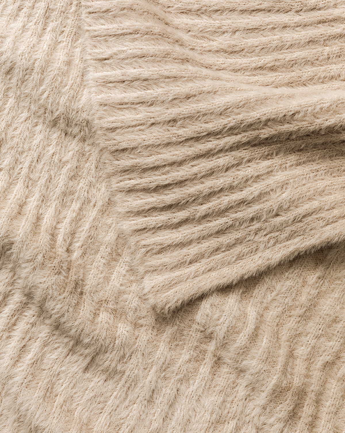 A close-up of the Caro Throw reveals its soft, beige ribbed knit with diagonal lines—perfect for bringing cozy, stylish home decor to any room, by McGee & Co.