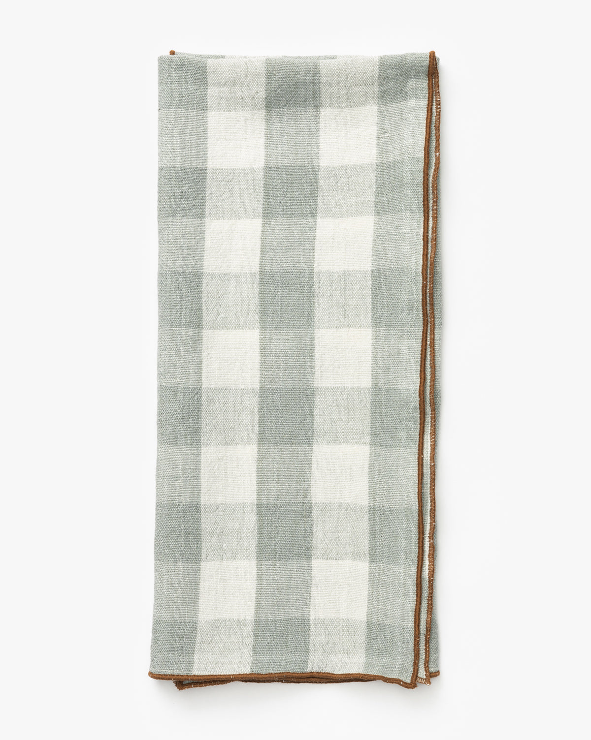 The Charlie Check Tea Towel features a folded rectangular design with a light gray and white checkered linen pattern and brown stitched border, ideal for elegant table settings, shown on a white background, by McGee & Co.