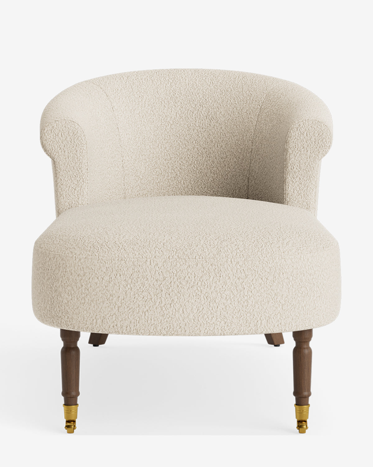 The Clemence Chaise is a cream-colored, upholstered accent chair featuring a rounded backrest, curved arms, and four wooden legs (two with brass casters), offering customizable elegance reminiscent of a classic chaise lounge for any interior, by McGee & Co.