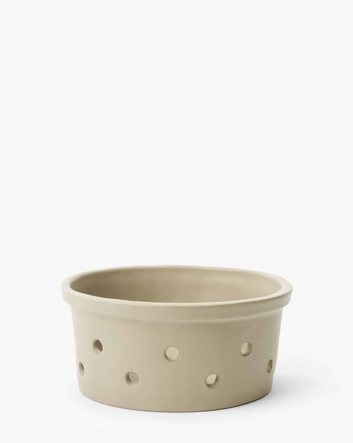 The Coen Berry Bowl is a round, beige stoneware bowl with a matte finish and several evenly spaced circular holes around its sides, shown against a plain white background by McGee & Co.