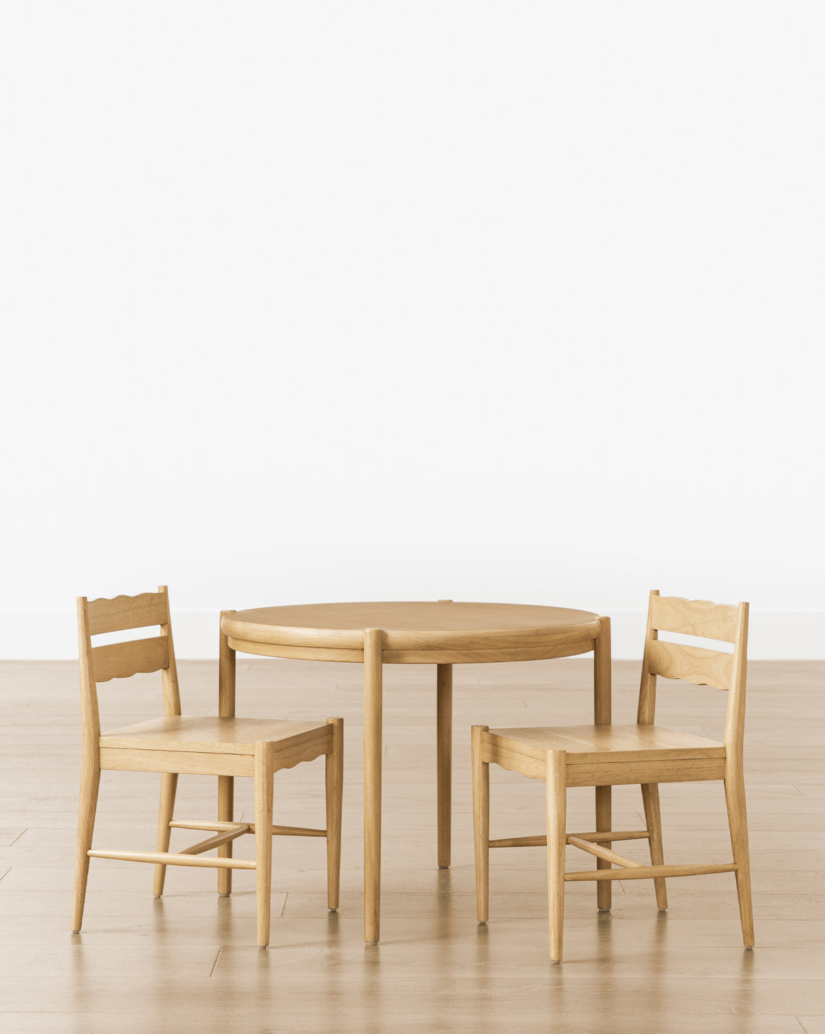 A round wooden table with a set of 2 Darcy Kids Chairs, placed on a light wood floor against a white background—perfect stylish kids play chairs for any playroom, by McGee & Co.