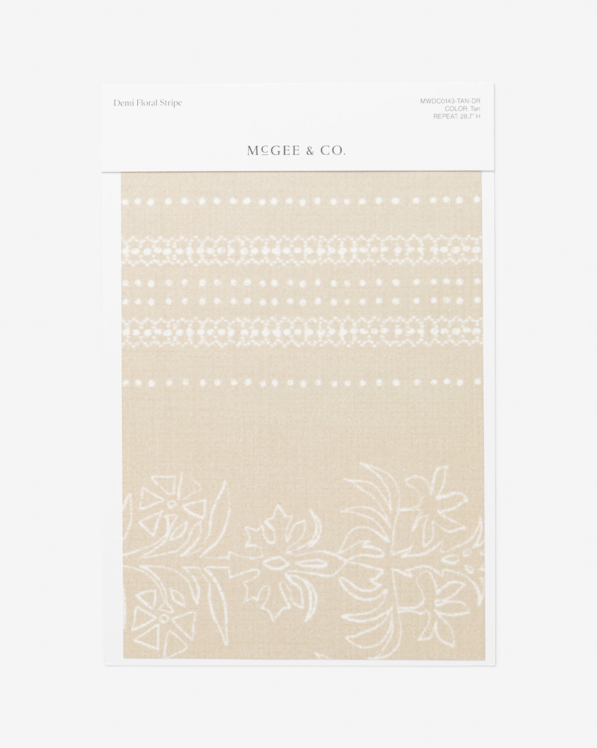 A Demi Floral Stripe Wallpaper Swatch by McGee & Co. shows a tan background with white floral and dotted stripes, reminiscent of elegant wallpaper. The fabric sample is attached to a white card featuring product details at the top, and is branded with McGee & Co.