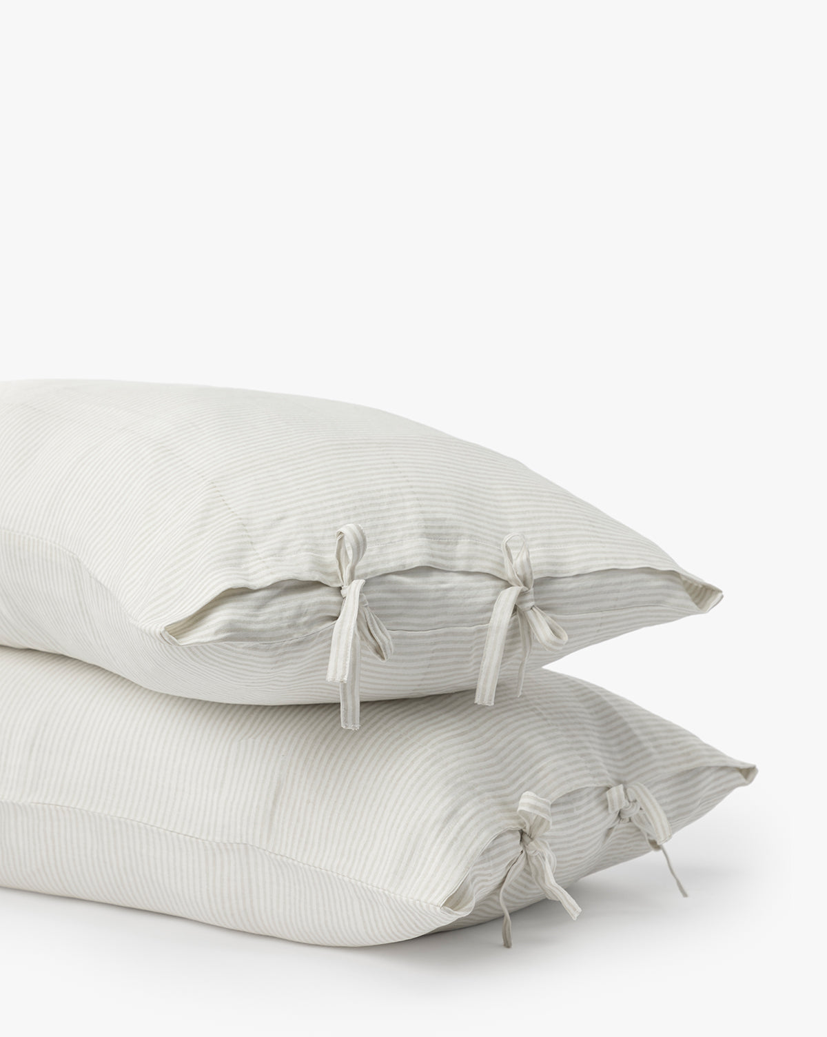 Two Easton Striped Shams (Set of 2) in cream, featuring subtle stripes and fabric ties at each end for a classic, elegant look, are stacked together against a plain white background.