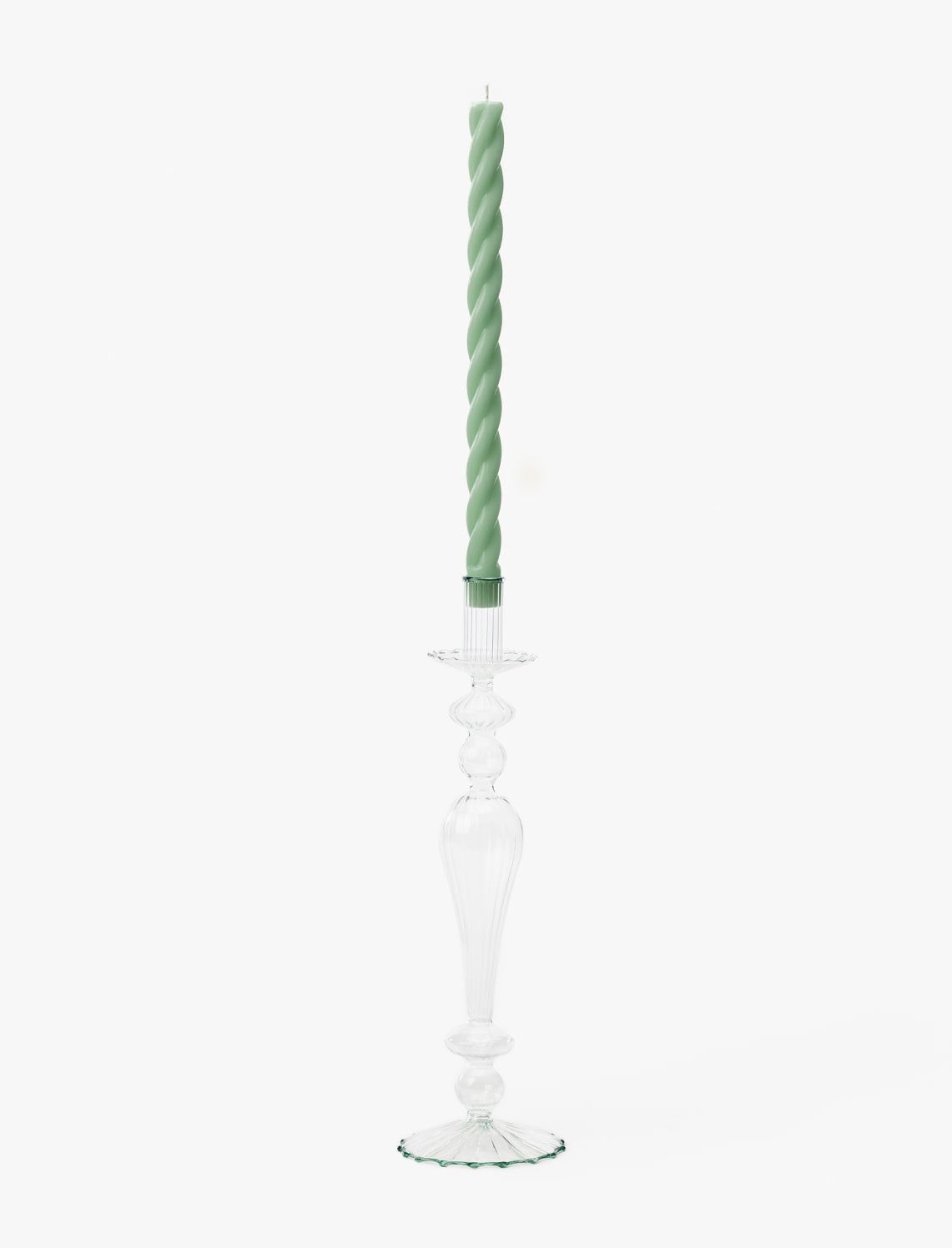 A tall, clear glass taper holder with a decorative design holds a light green twisted candle against a plain white background, resembling the McGee & Co. x Loeffler Randall Effie Taper Holder by McGee & Co.