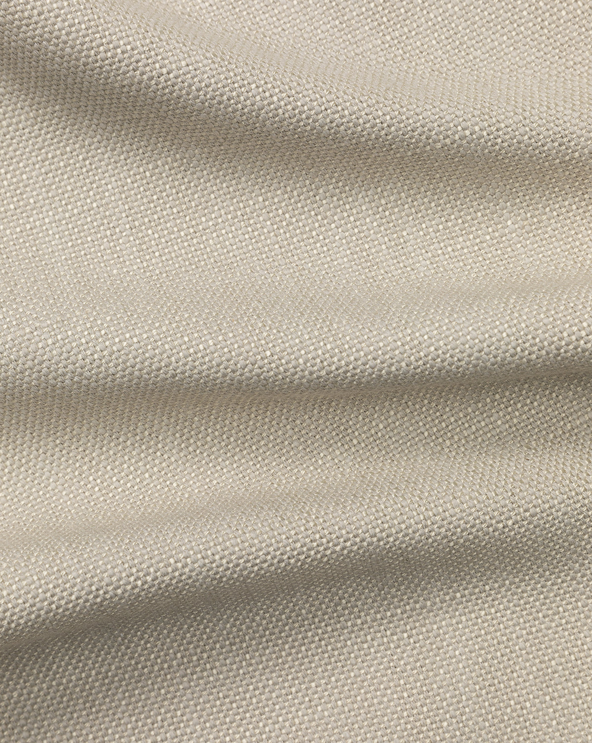 Close-up of the Perennials Upholstery Swatch in beige, featuring visible texture and small raised bumps. Soft folds and gentle shadows highlight the detailed weave and natural look of this performance fabric.