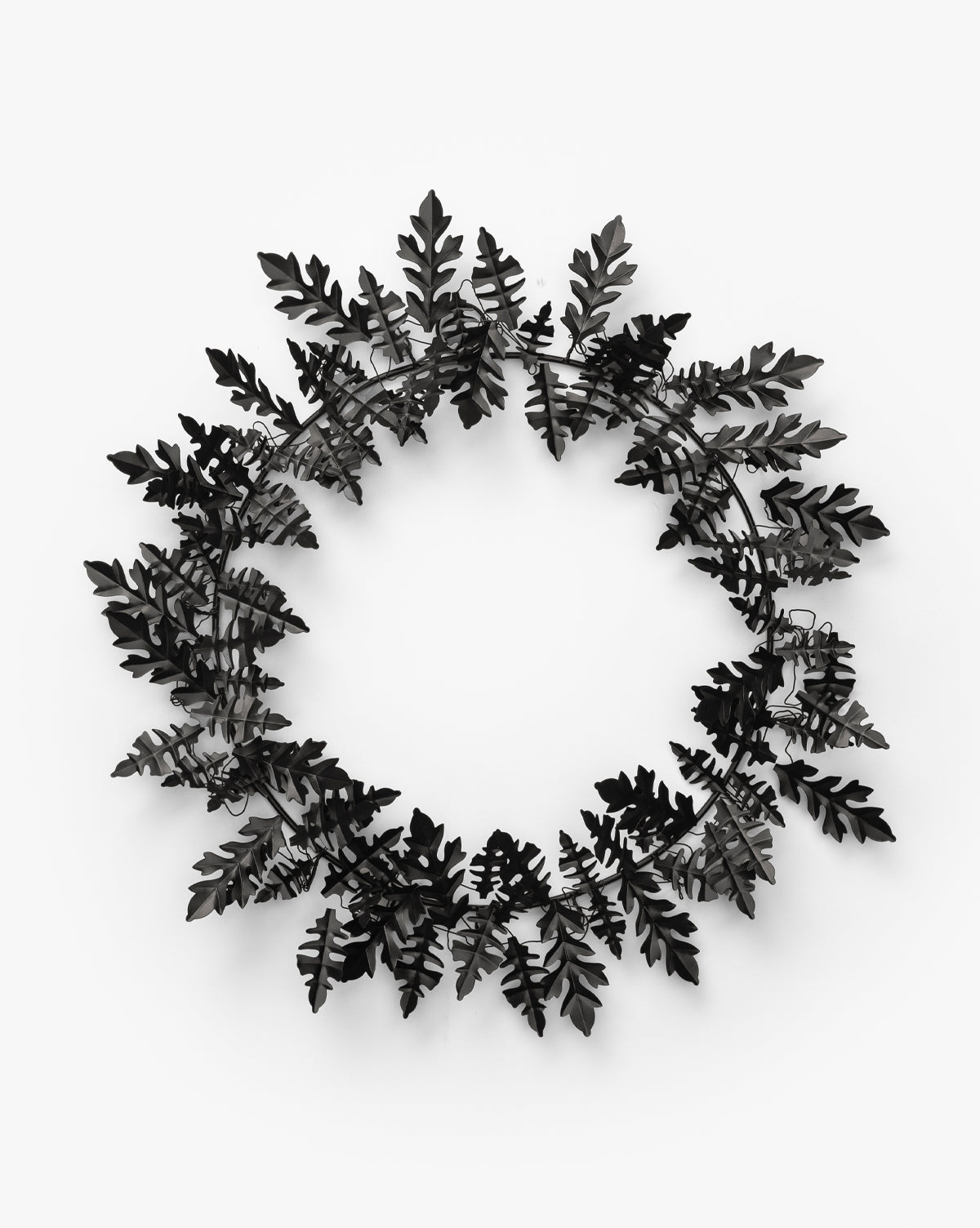 The Endora Metal Wreath features black metal oak leaves in a circular design, ideal for modern harvest styling or as bold seasonal décor, by McGee & Co. Shown here against a plain white background.
