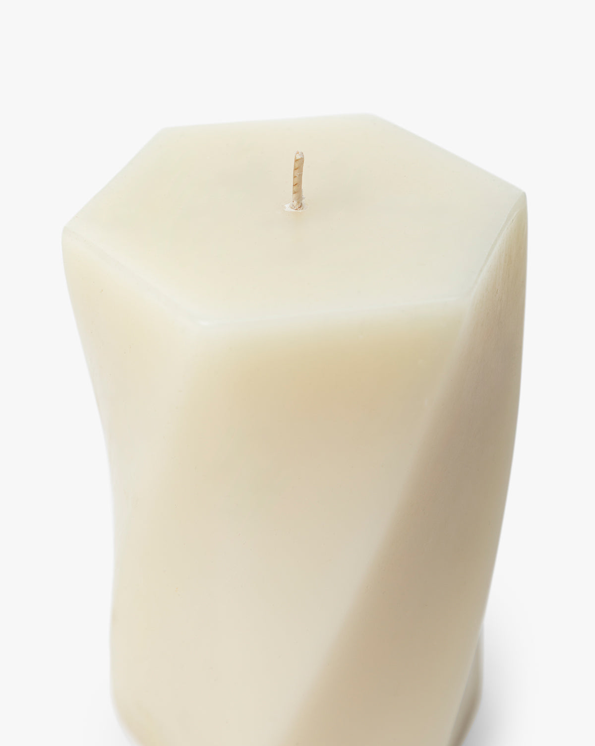 The Errol Wax Pillar Candle is a white, hexagon-shaped sculptural candle featuring a twisted design and single wick, set against a plain white background by McGee & Co.