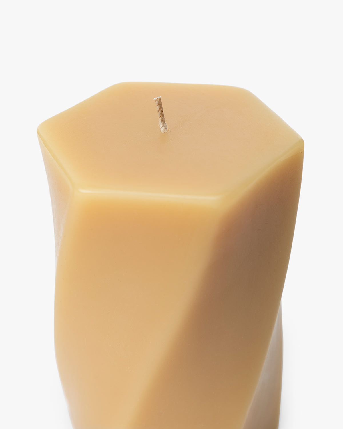A close-up of the Errol Wax Pillar Candle, a beige modern piece with smooth, angled sides, geometric shape, and a single centered wick for a contemporary sculptural look, by McGee & Co.