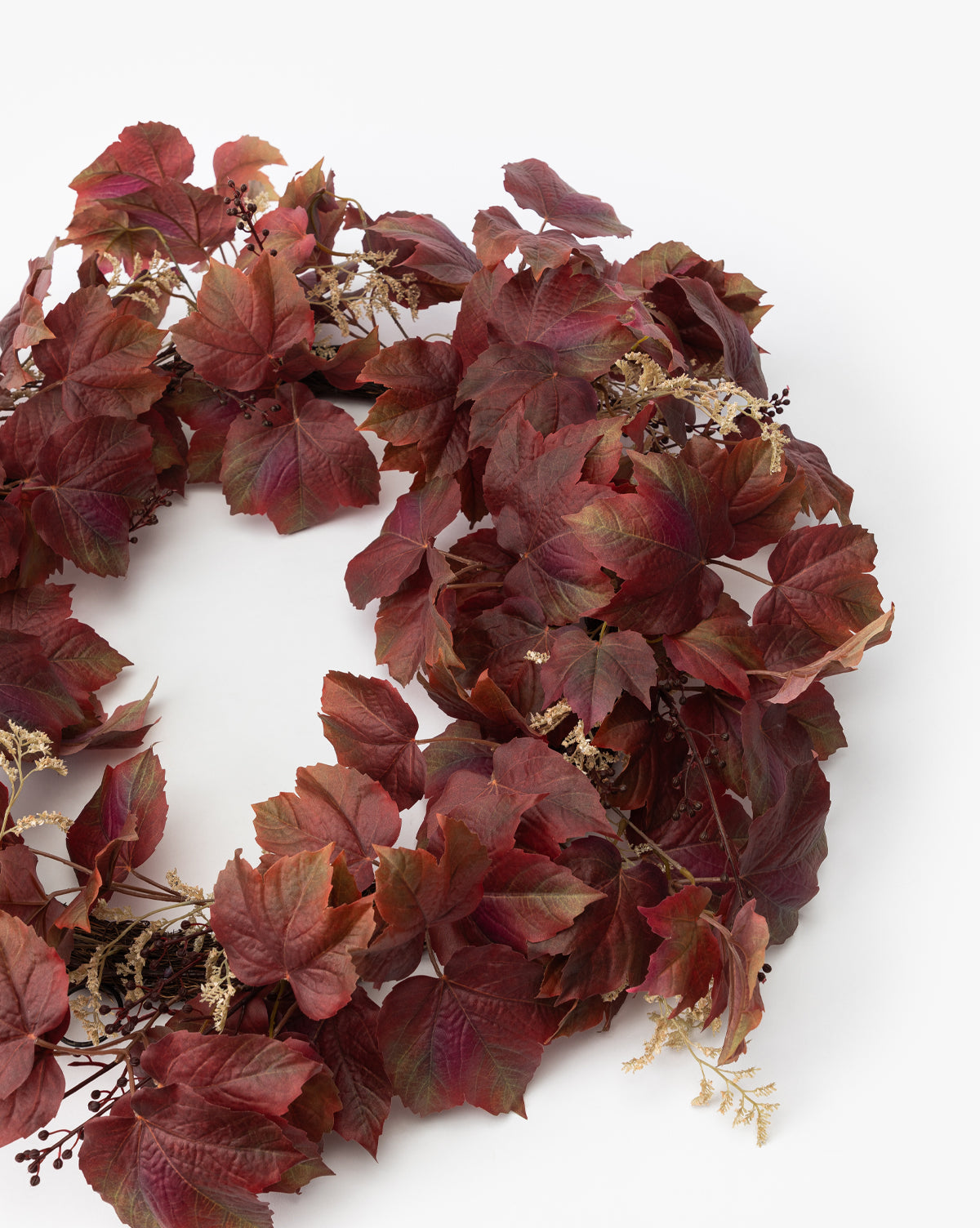 The Faux Autumn Grapevine Wreath features deep red and burgundy leaves with beige dried flowers, artfully arranged for lasting seasonal decor. Ideal autumn accent with lifelike foliage for your home.