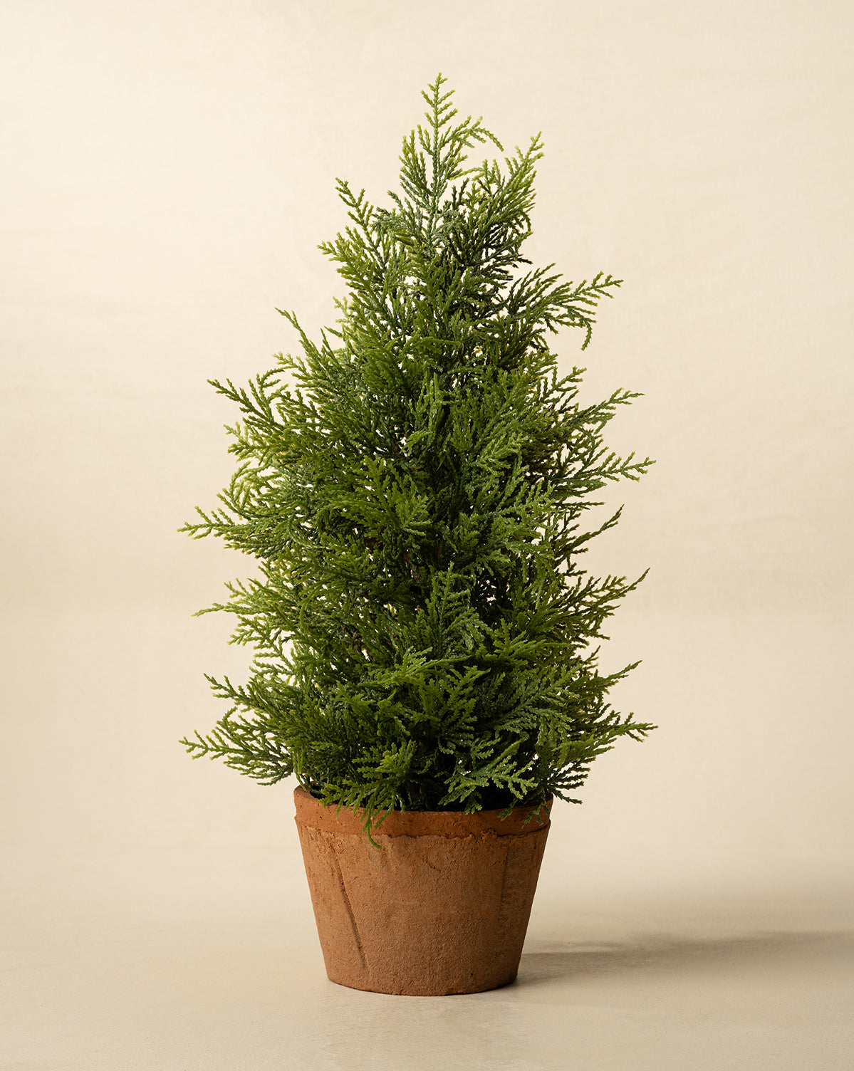 The 17" Cypress Faux Potted Tree features dense, needle-like green foliage and comes in a terracotta pot, perfect for adding a touch of greenery to any room, by McGee & Co.