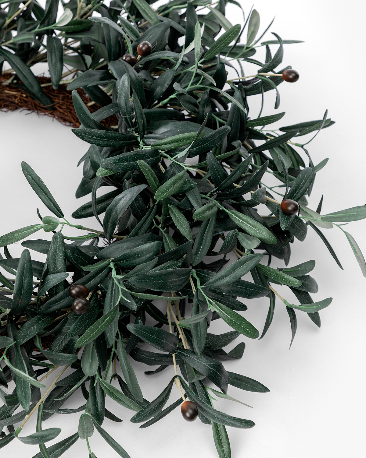 A close-up of the Faux Olive Berry Wreath, showcasing lifelike dark green artificial olive leaves and small round brown berries against a white background, by McGee & Co.