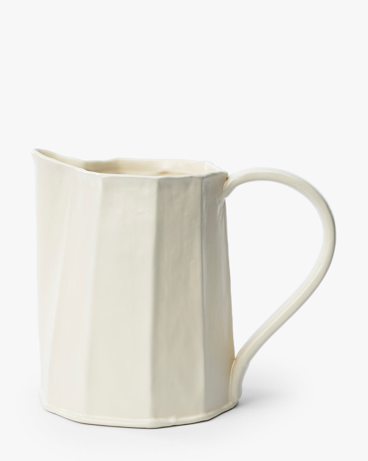 The Fielding Ceramic Pitcher features a cream-colored stoneware body with a faceted, angular surface and a large curved handle, making it ideal for rustic kitchen decor, by McGee & Co. Shown against a plain white background.