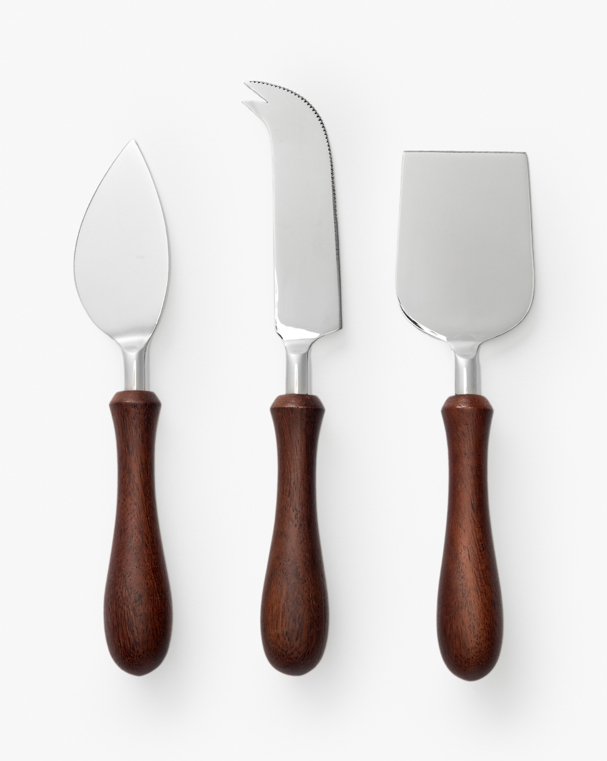 The Fromagerie Cheese Knives (Set of 3) features wooden handles and stainless steel blades: a pointed knife, a fork-tipped serrated knife, and a wide flat chisel—essential tools for entertaining on any occasion, by McGee & Co.