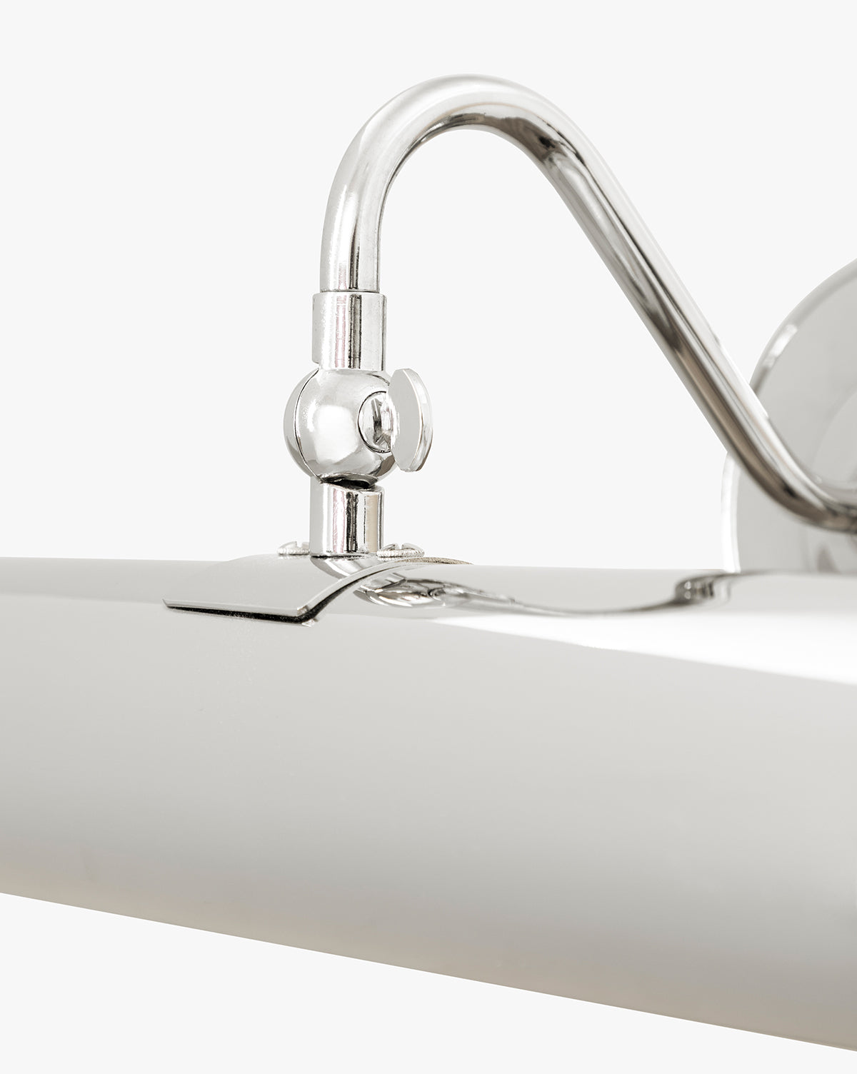 Close-up of the Gallery Picture Sconce, featuring a curved arm and cylindrical shade in burnished bronze, mounted on a plain white wall by McGee & Co.