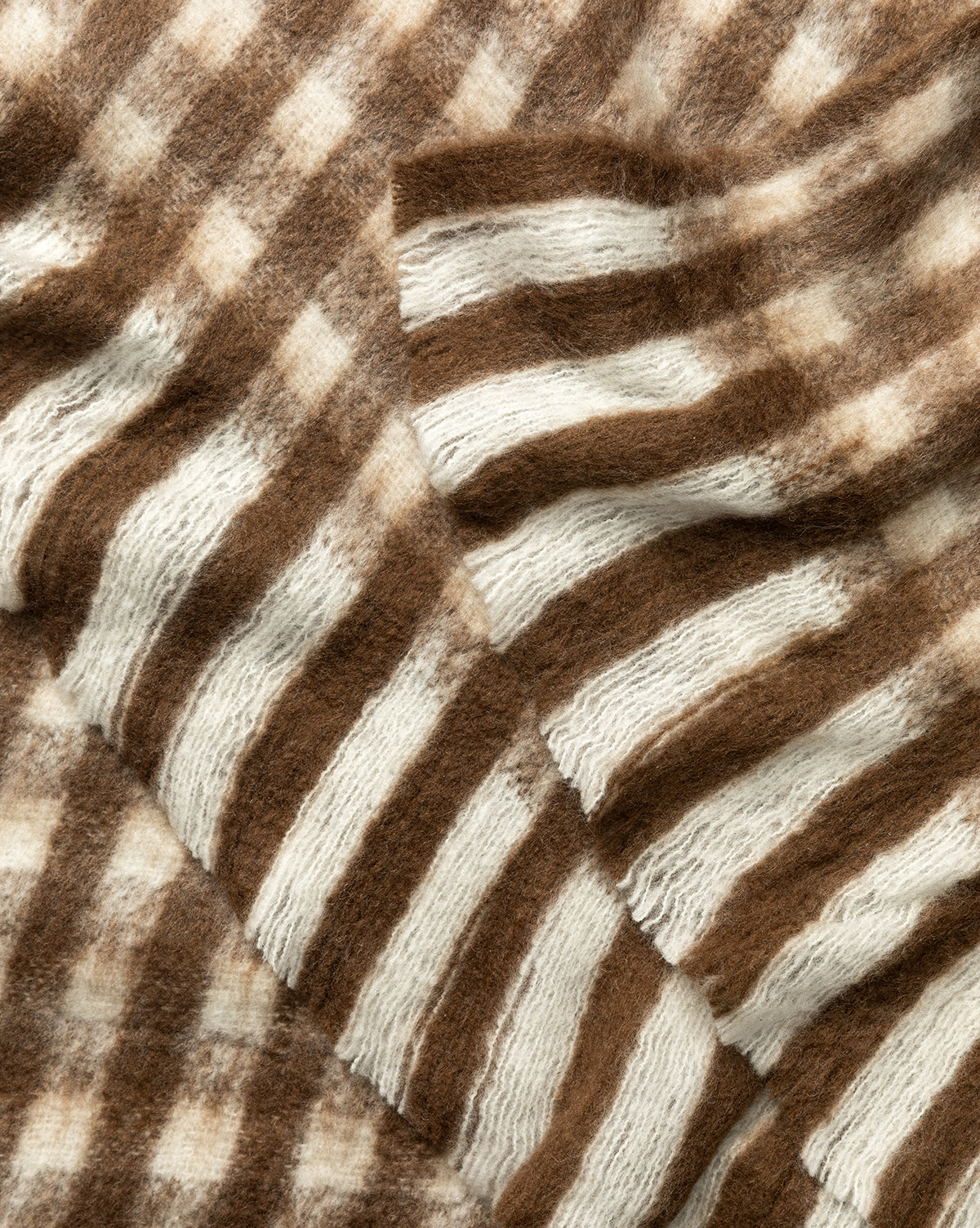 Close-up of the Indaba Gingham Wool Blend Throw, featuring soft, fuzzy fabric with brown and white horizontal stripes arranged in overlapping layers for a cozy, textured look. McGee & Co.