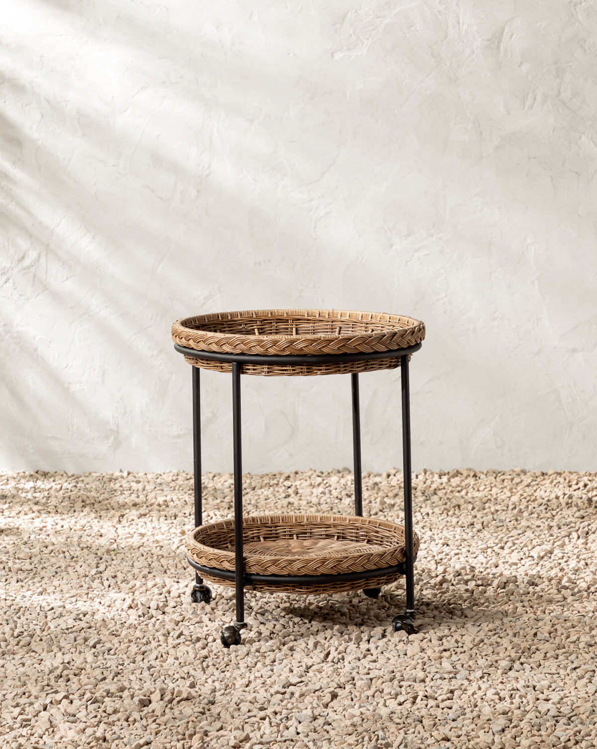 Set on a pebble floor by a textured white wall, sunlight casts soft shadows—ideal for stylish outdoor entertaining, by McGee & Co.