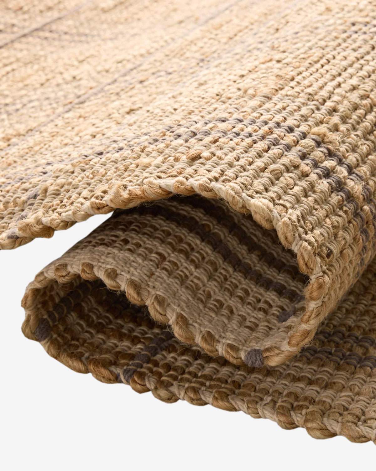 A close-up of the Judy Jute Rug Collection No. 2 showcases its handwoven, thick braided natural fibers in earthy brown tones and textured surface, all in a neutral palette, by McGee & Co.