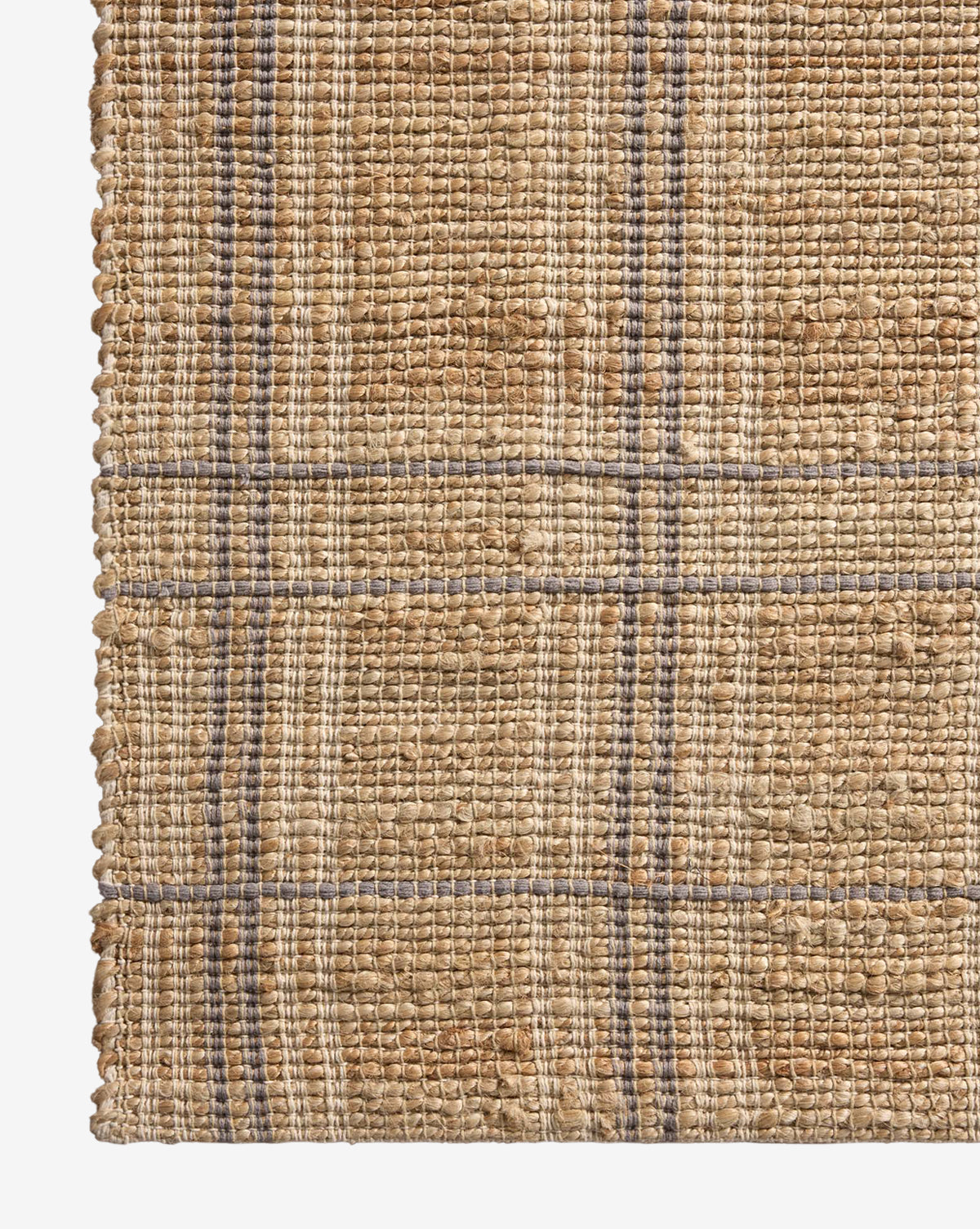 Close-up of the Judy Jute Rug Collection No. 2, a handwoven rug in tan and beige with thin blue and gray lines forming a simple, textured plaid grid pattern, by McGee & Co.
