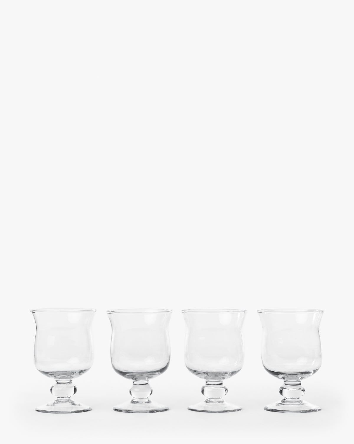 The Keely Goblets (Set of 4) are clear recycled glass goblets with short stems, evenly spaced in a row against a white background—ideal for modern dining, by McGee & Co.