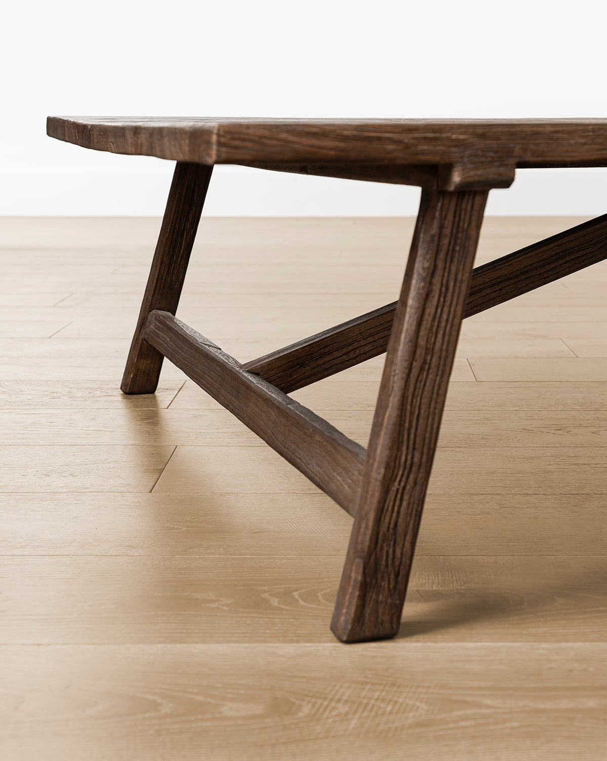 Close-up of the legs and edge of the Lockwood Coffee Table with a natural finish, set on a light-toned wood floor against a plain white background, by McGee & Co.