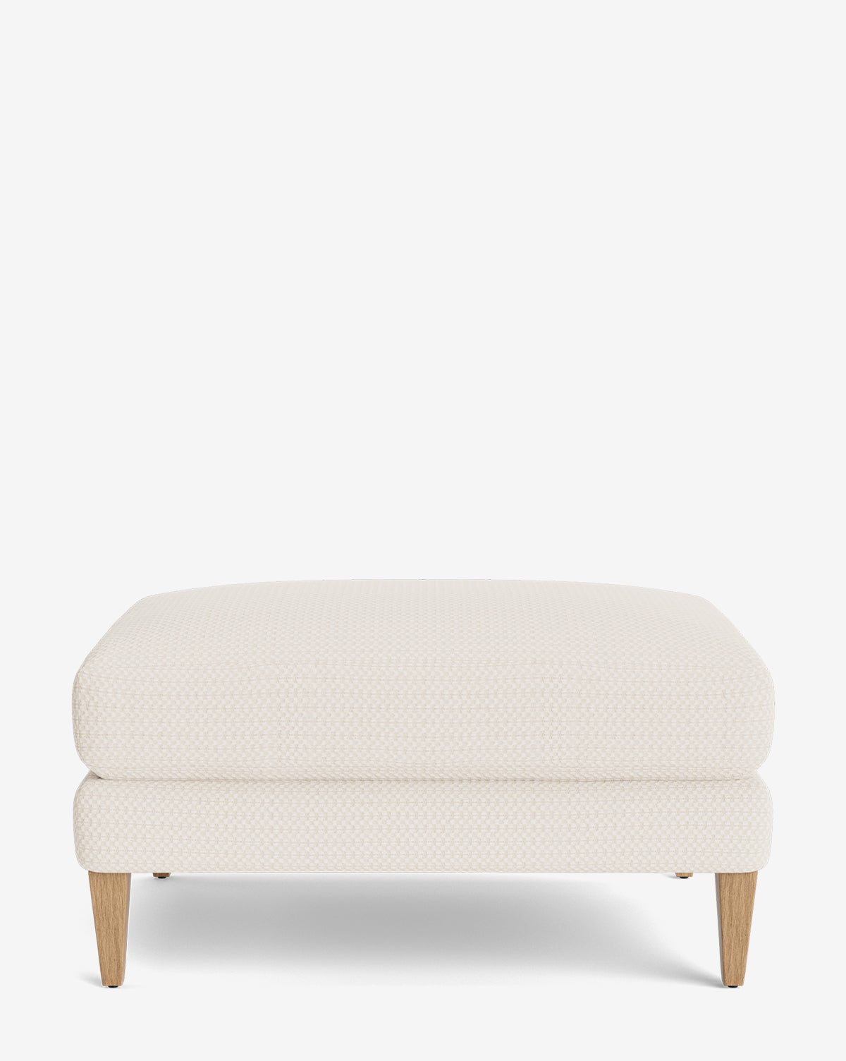 The Lucille Ottoman, with customizable light beige upholstery and four light wooden legs, adds a modern touch, by McGee & Co. Displayed on a plain white background.