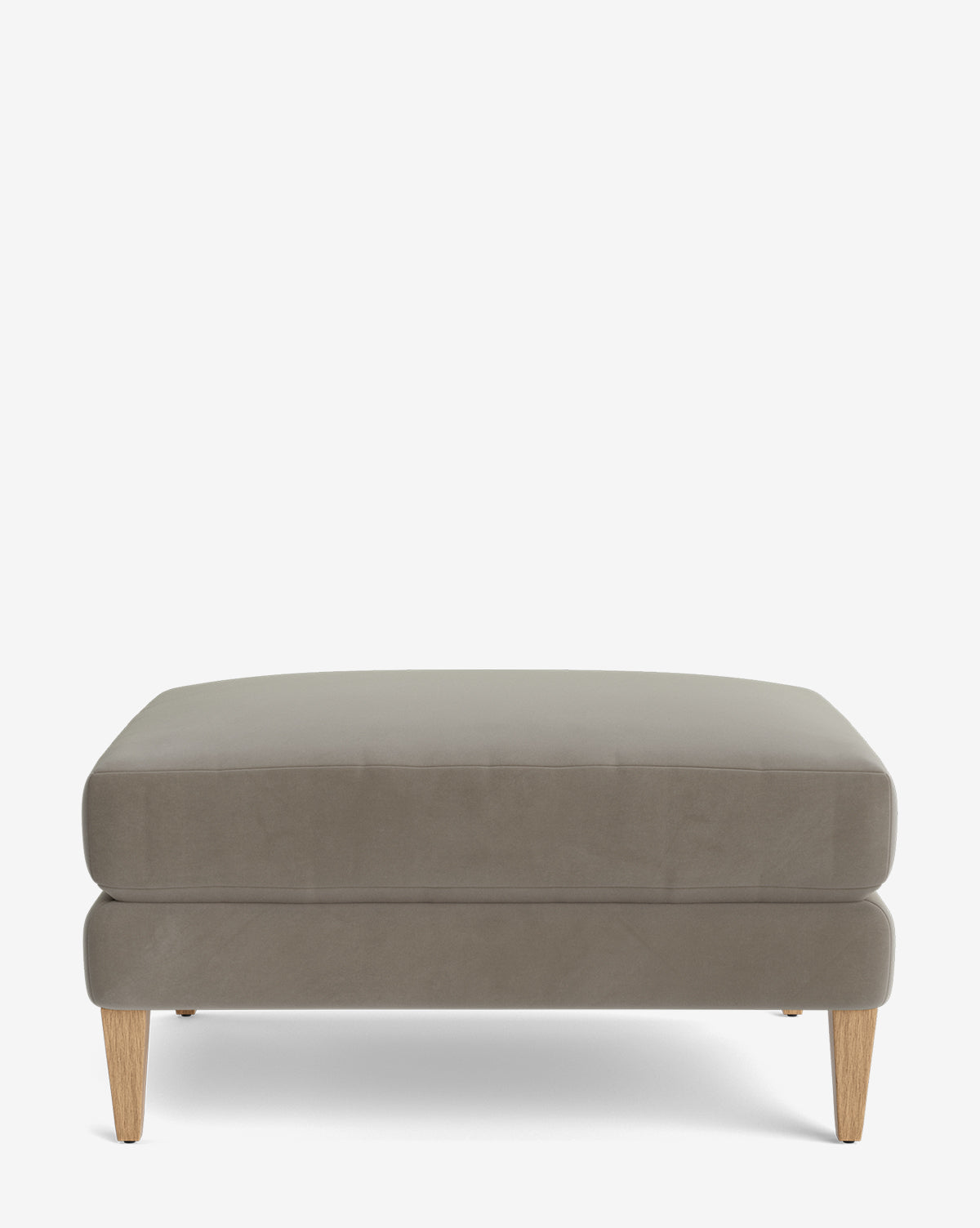 The Lucille Ottoman features modern light brown upholstery and four angled wooden legs, displayed on a plain white background, by McGee & Co.