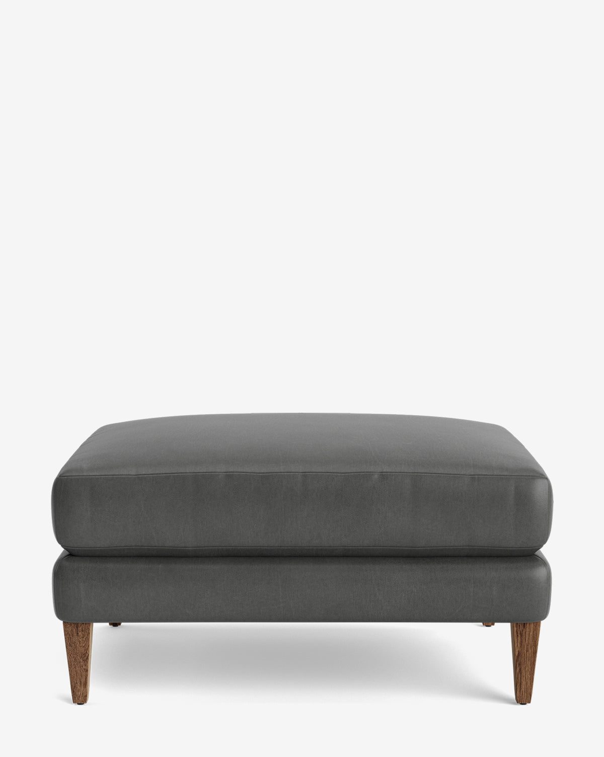 The Lucille Ottoman is a modern rectangular ottoman with dark gray upholstery, wooden legs, and customizable options, shown against a plain white background, by McGee & Co.
