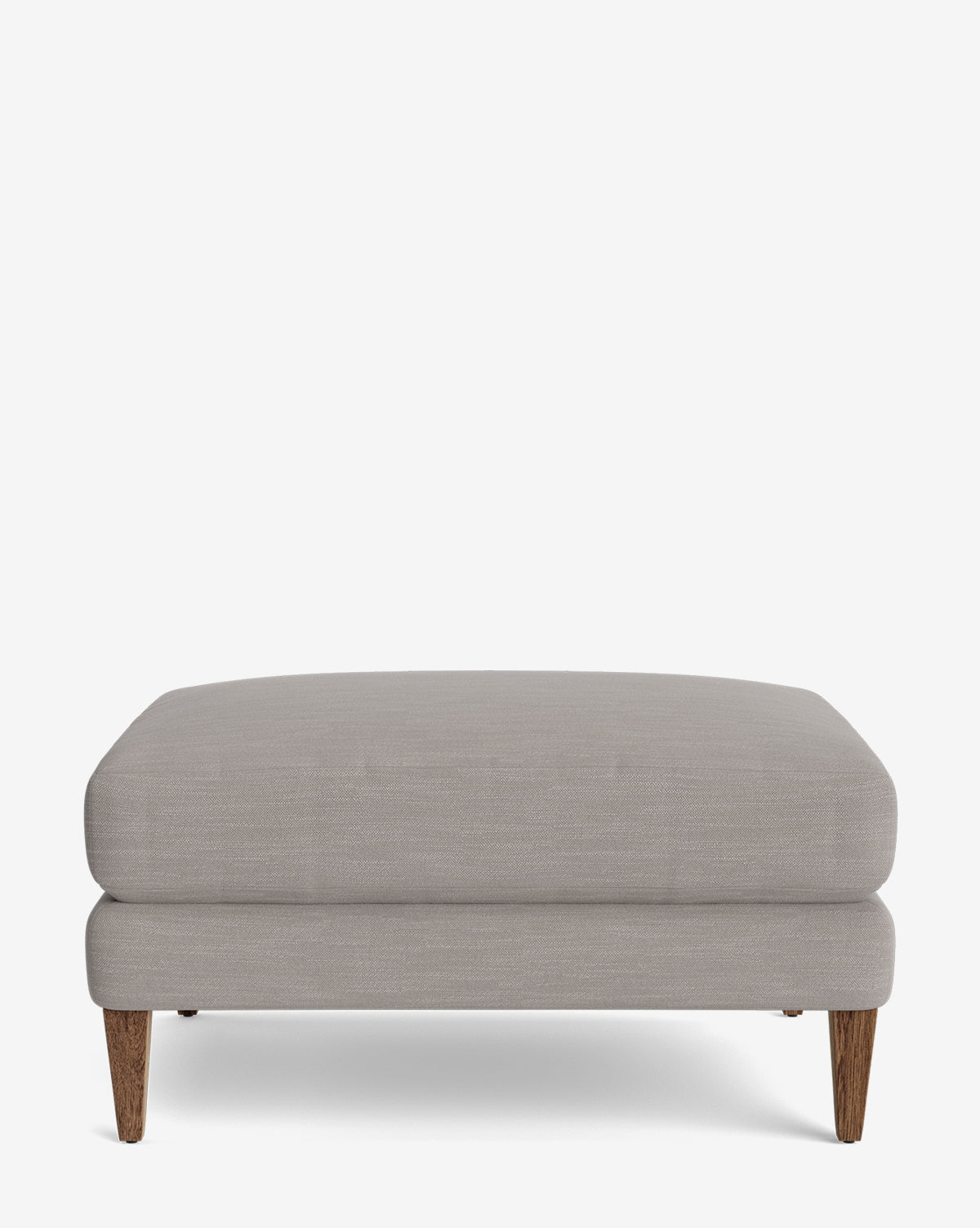 The Lucille Ottoman is a modern, rectangular ottoman in light gray upholstery with short wooden legs, shown against a plain white background, by McGee & Co.