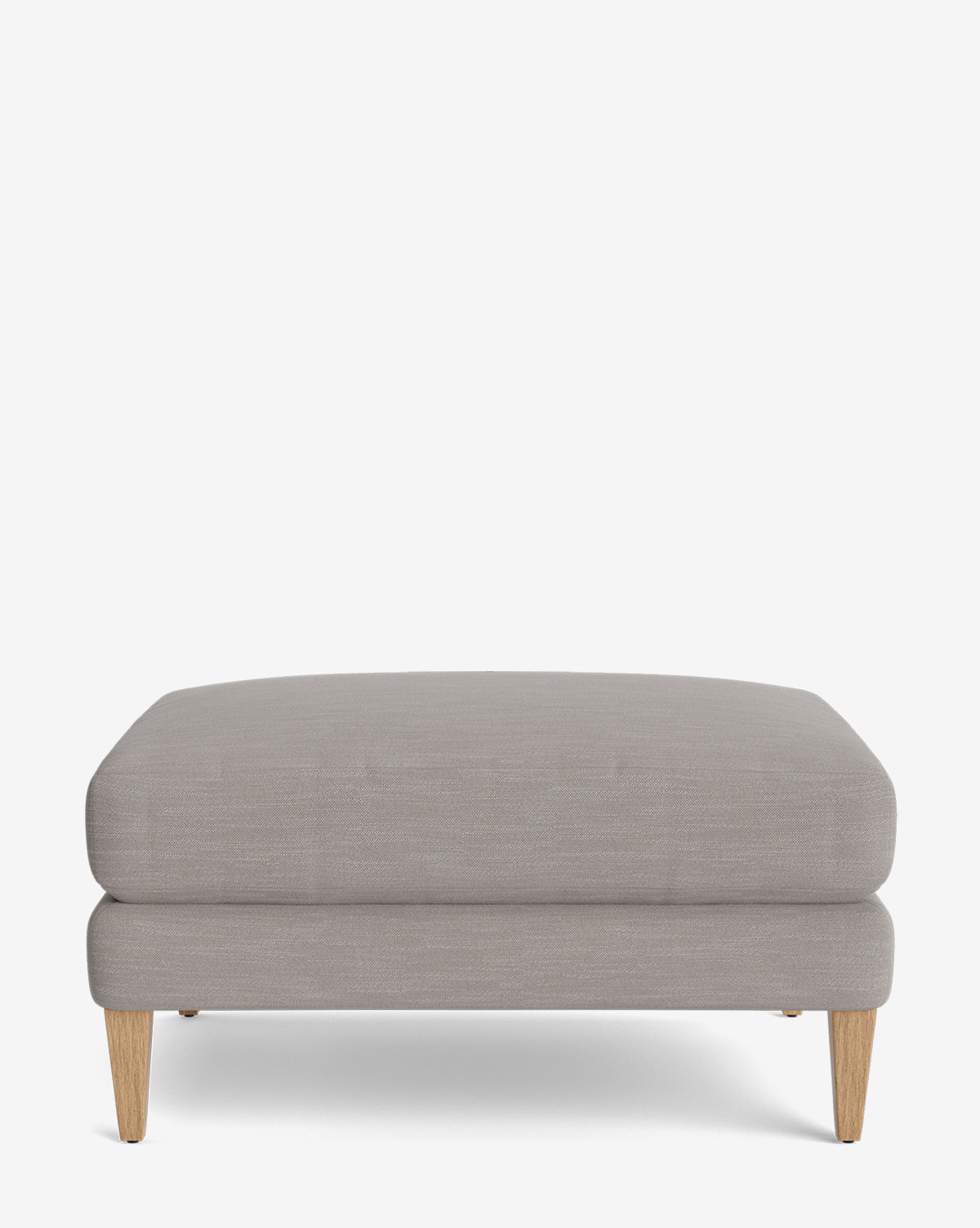 The Lucille Ottoman features light gray upholstery and four short, angled wooden legs, shown against a plain white background—a stylish and customizable choice for modern spaces, by McGee & Co.