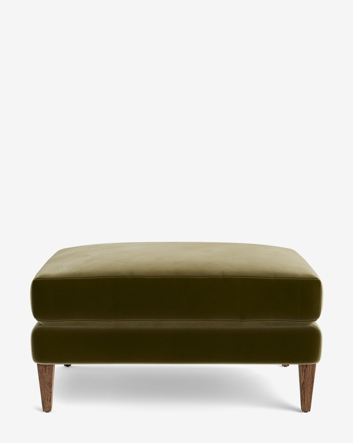 The Lucille Ottoman is a modern, square olive green velvet ottoman with short, angled wooden legs. Its versatile design allows for customization to complement your style and living space. Shown on a plain white background by McGee & Co.