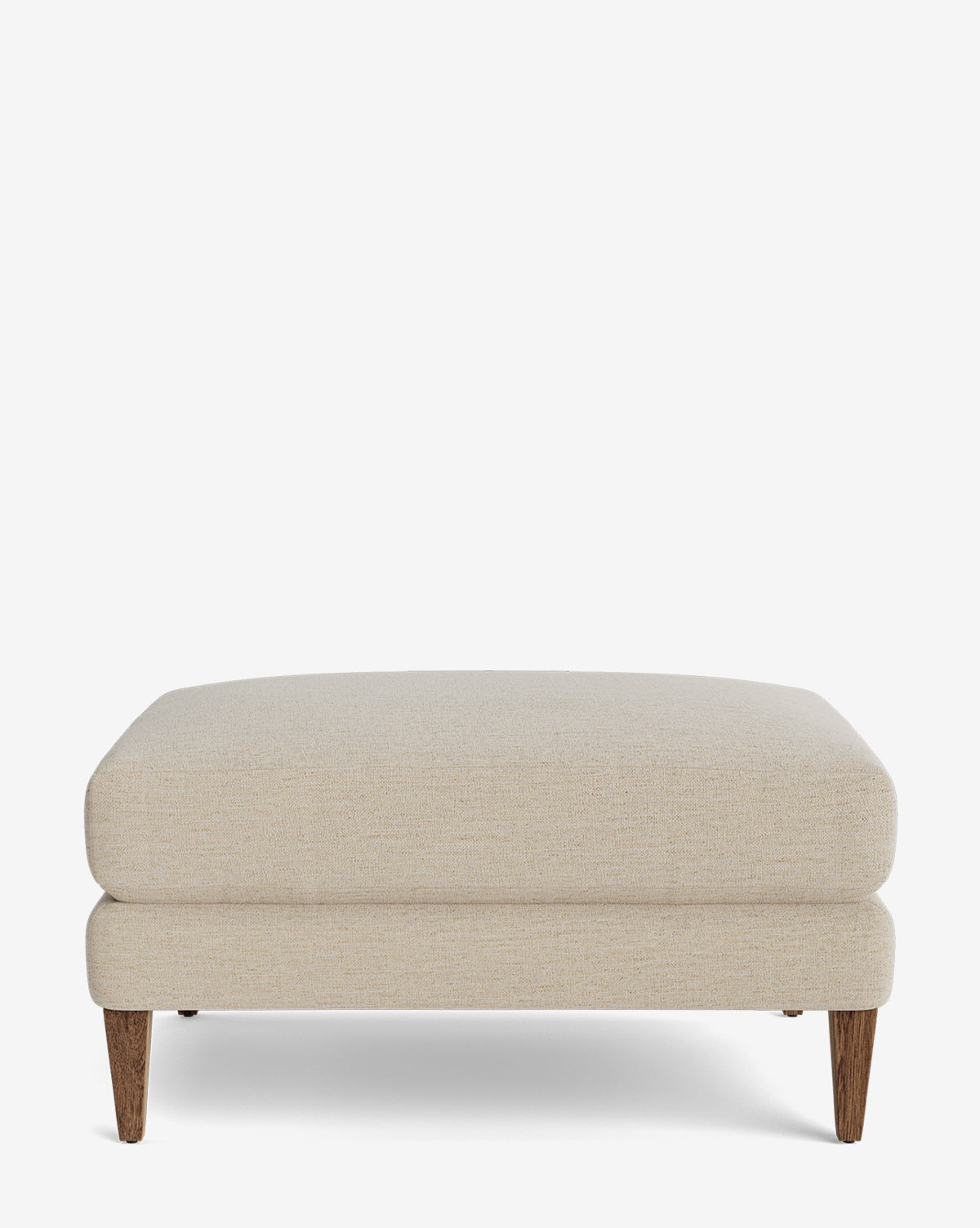 The Lucille Ottoman is a modern rectangular beige ottoman, featuring two stacked cushion layers and four tapered wooden legs, shown against a plain white background by McGee & Co.