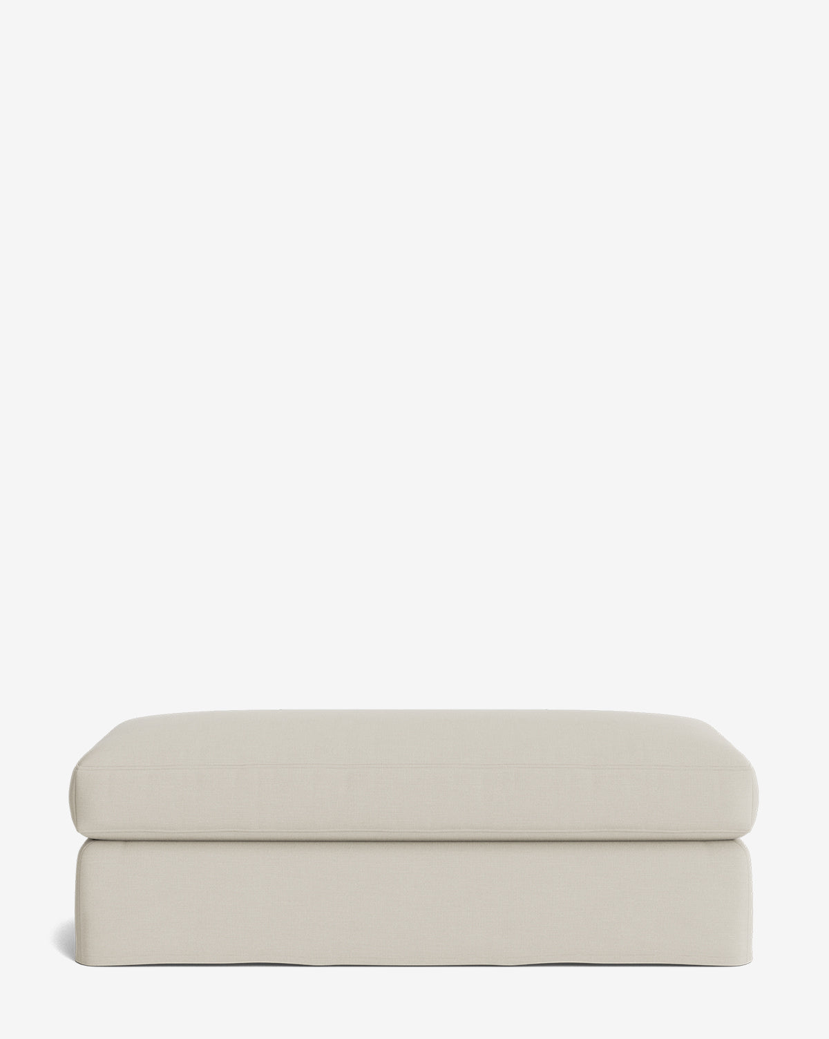 The Macy Slipcover Ottoman is a rectangular, light beige ottoman with soft, rounded edges and a smooth fabric surface—an elegant addition to any living room, shown here against a plain white background by McGee & Co.