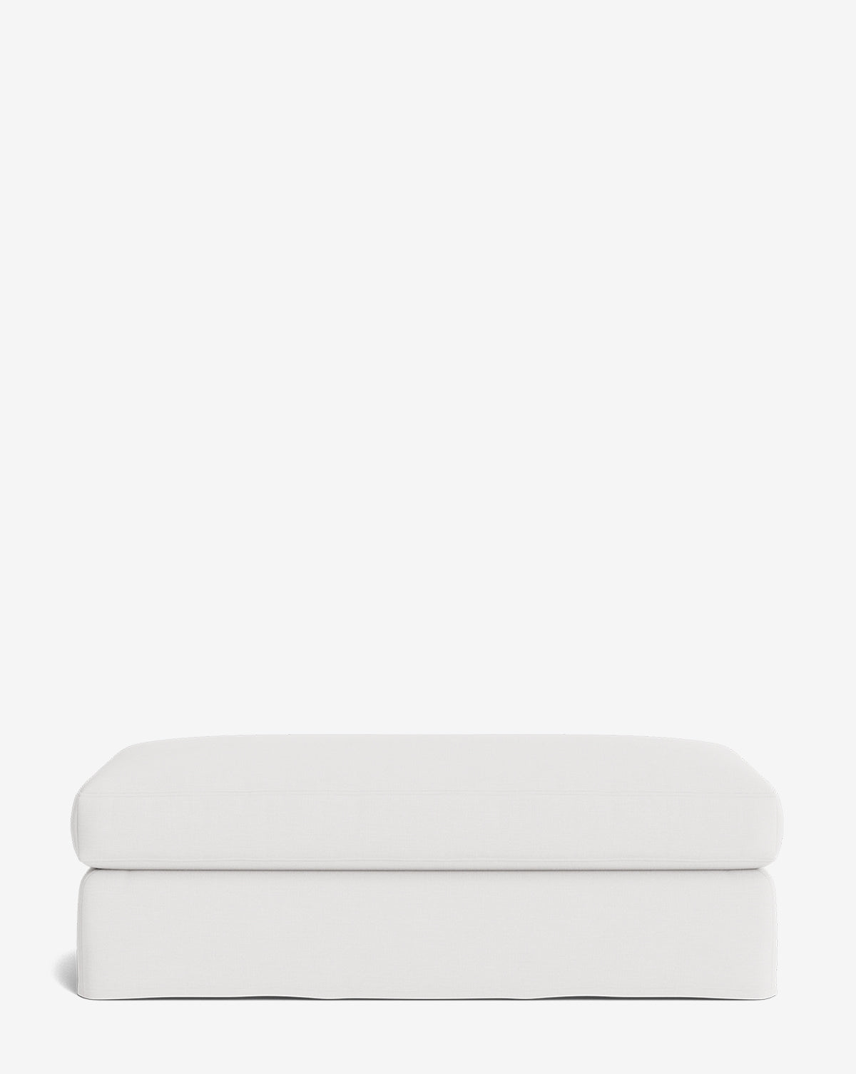 The Macy Slipcover Ottoman is a minimalist, rectangular white ottoman with a soft cushioned top and smooth edges—an ideal, versatile addition to your living room decor, shown against a plain white background by McGee & Co.