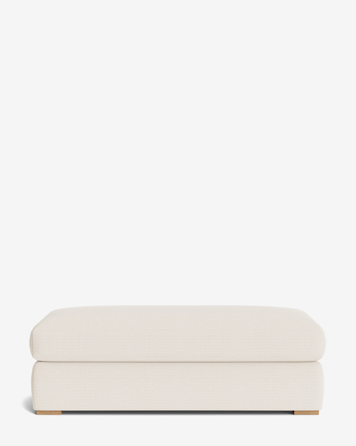 The Macy Upholstered Ottoman is a rectangular, low-profile piece in off-white fabric with smooth rounded edges, a minimalist design, and small wooden feet visible at the bottom corners—perfect for modern living rooms, by McGee & Co.