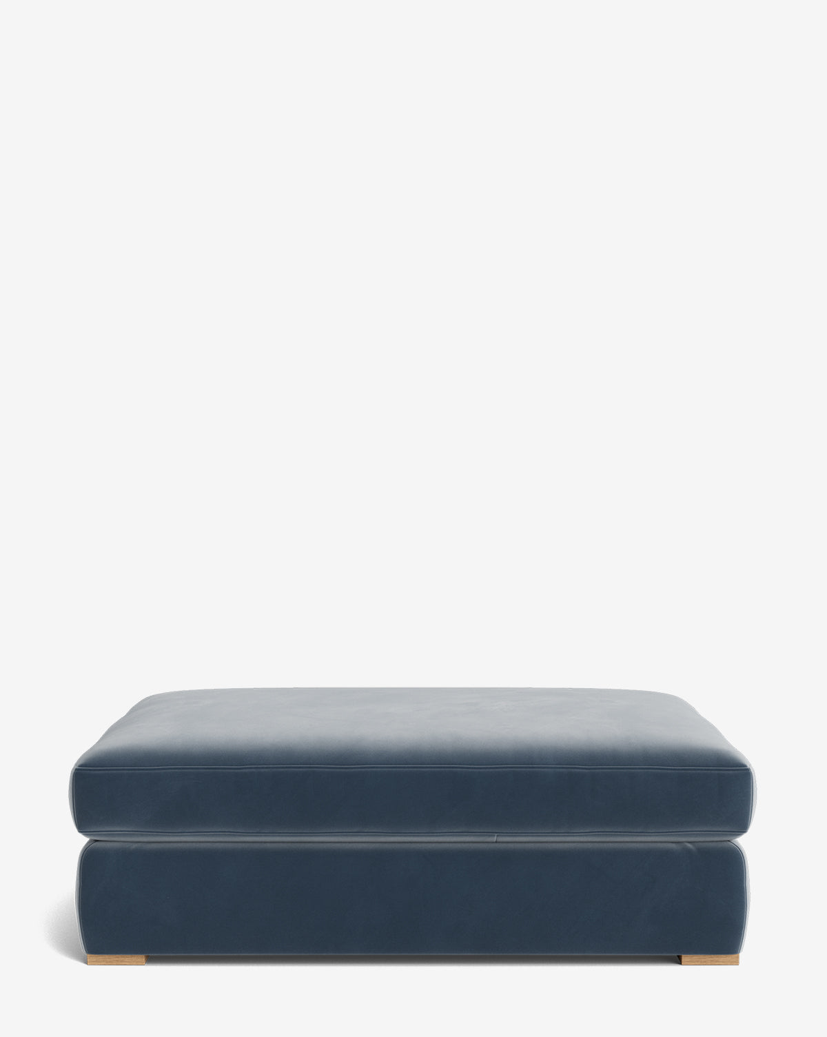 The Macy Upholstered Ottoman is a large, rectangular blue ottoman with a smooth upholstered surface and wooden feet, ideal for living room furniture, shown against a plain white background, by McGee & Co.